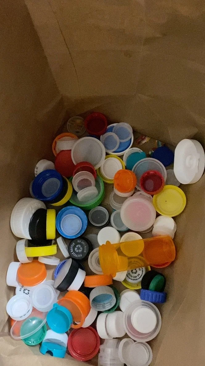 A collection of various plastic bottle caps in different colors and sizes inside a paper bag.