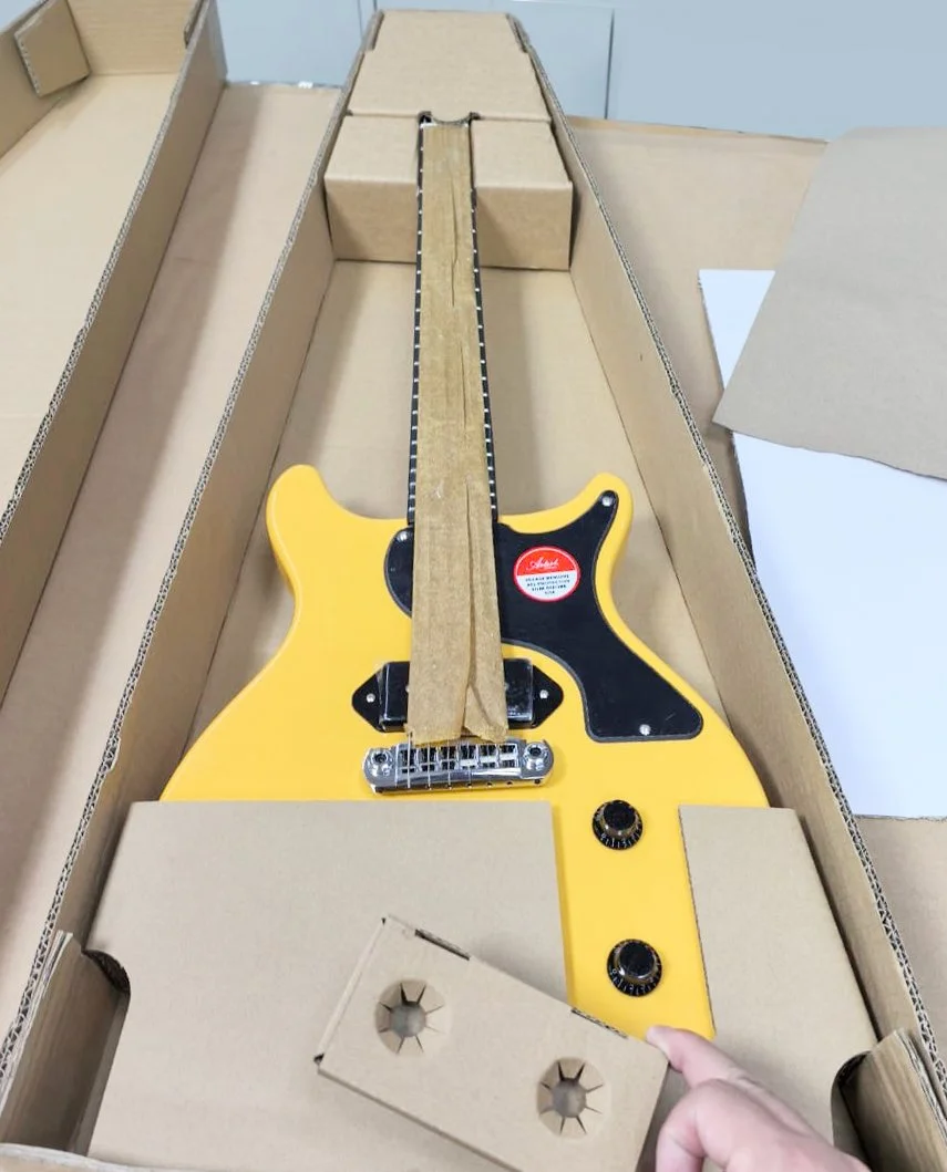 Fibre-based protective guitar packaging made from corrugated and kraft paper components replacing plastic foam and bubble wrap