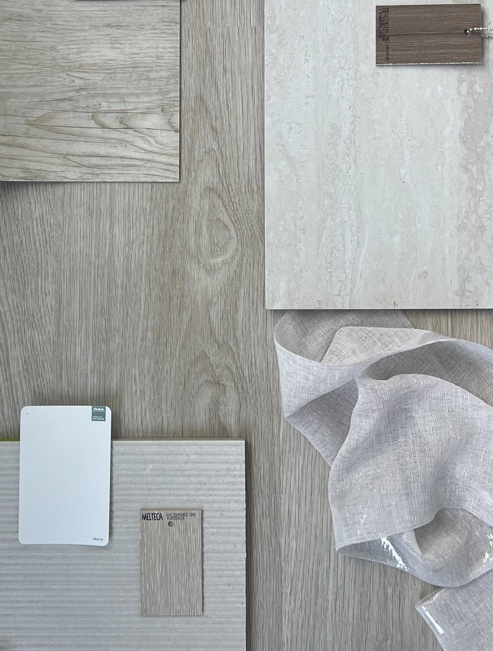 Flay Lay of Neutral Material Samples Including Vinyl Planking Flooring, Curtain Fabric, Tiles and Paint Swatch