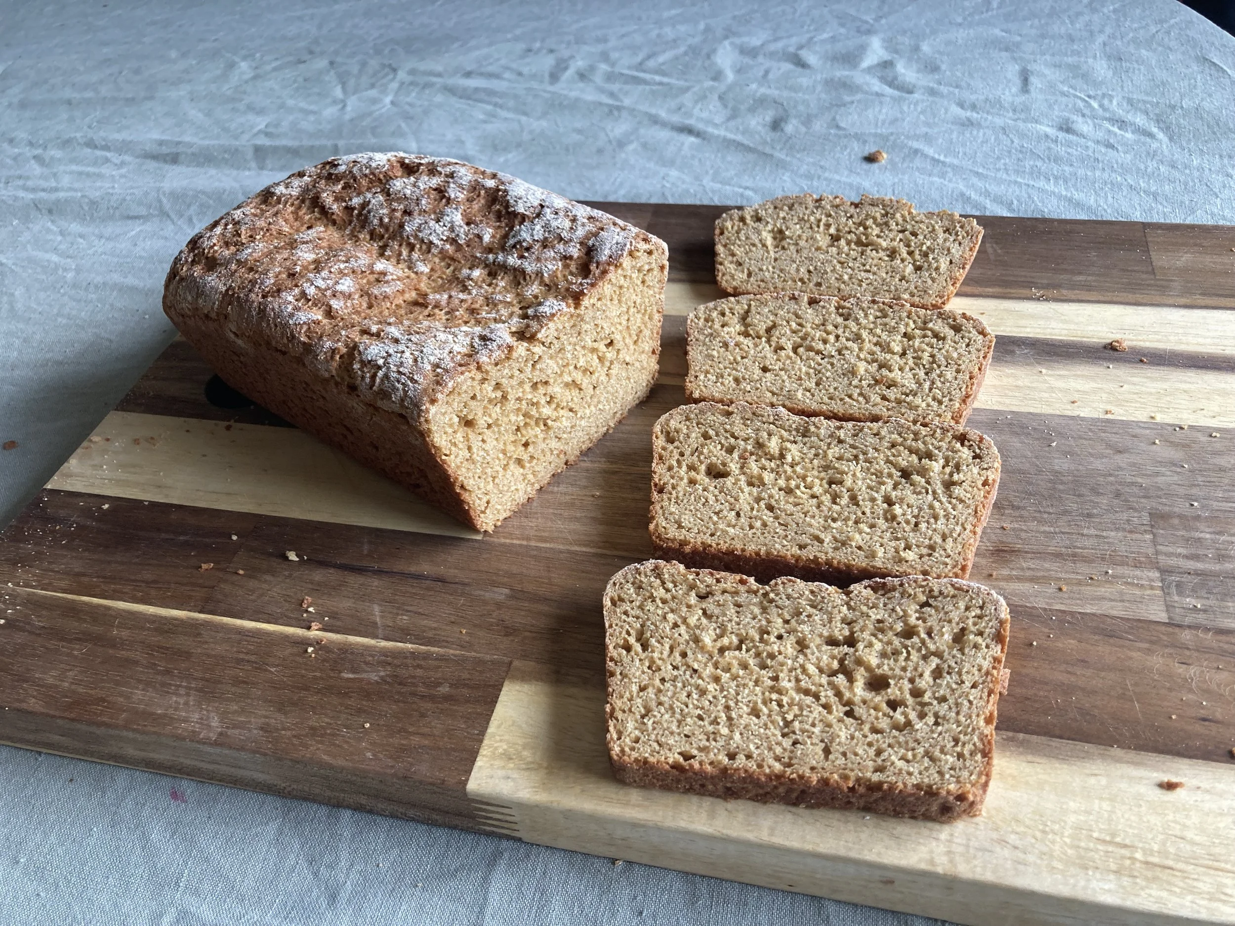 Sliced loaf of homemade organic, fresh-milled einkorn bread on a wooden cutting board