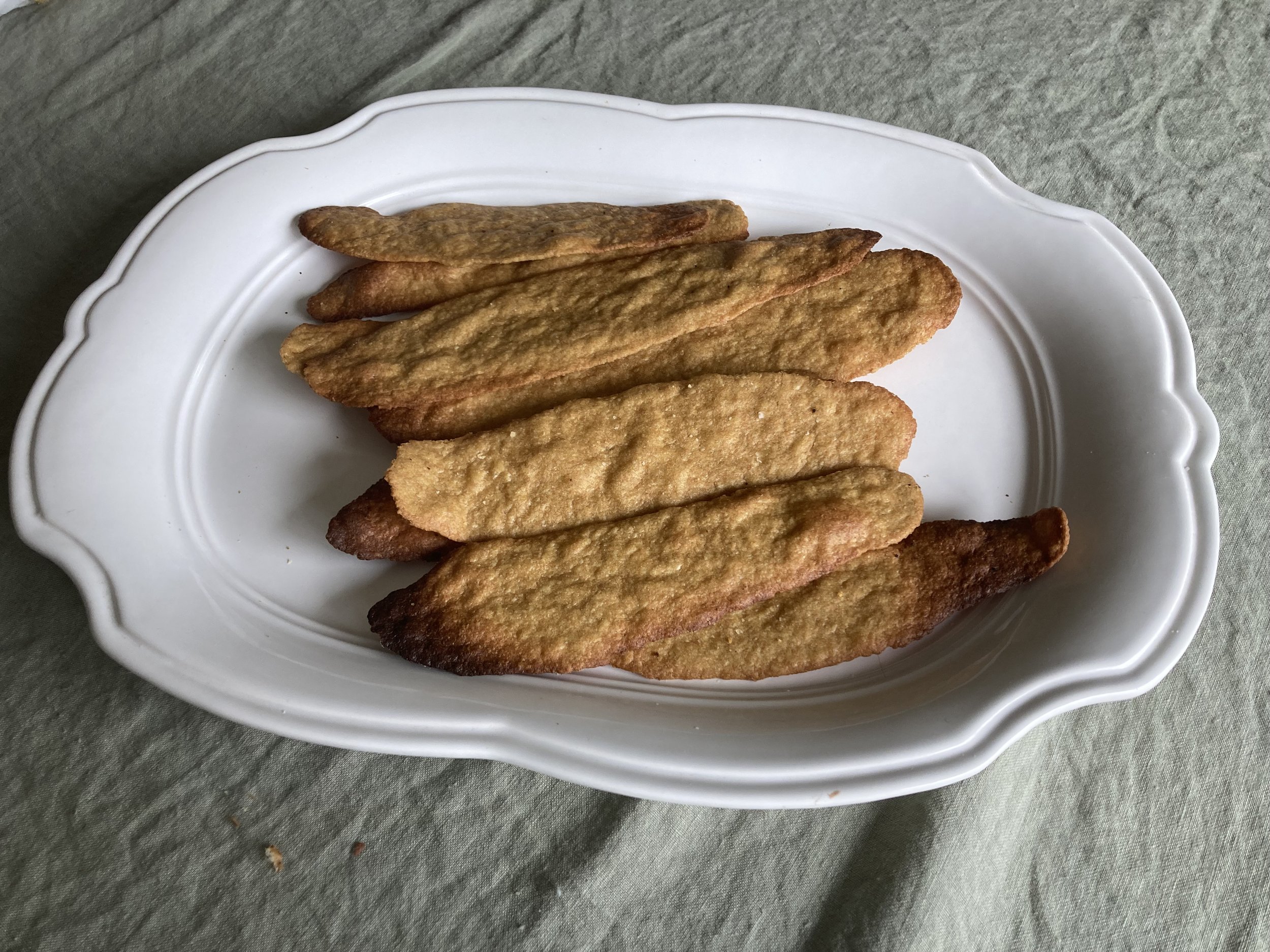 Organic fresh-milled einkorn flatbread crackers arranged on a white platter.