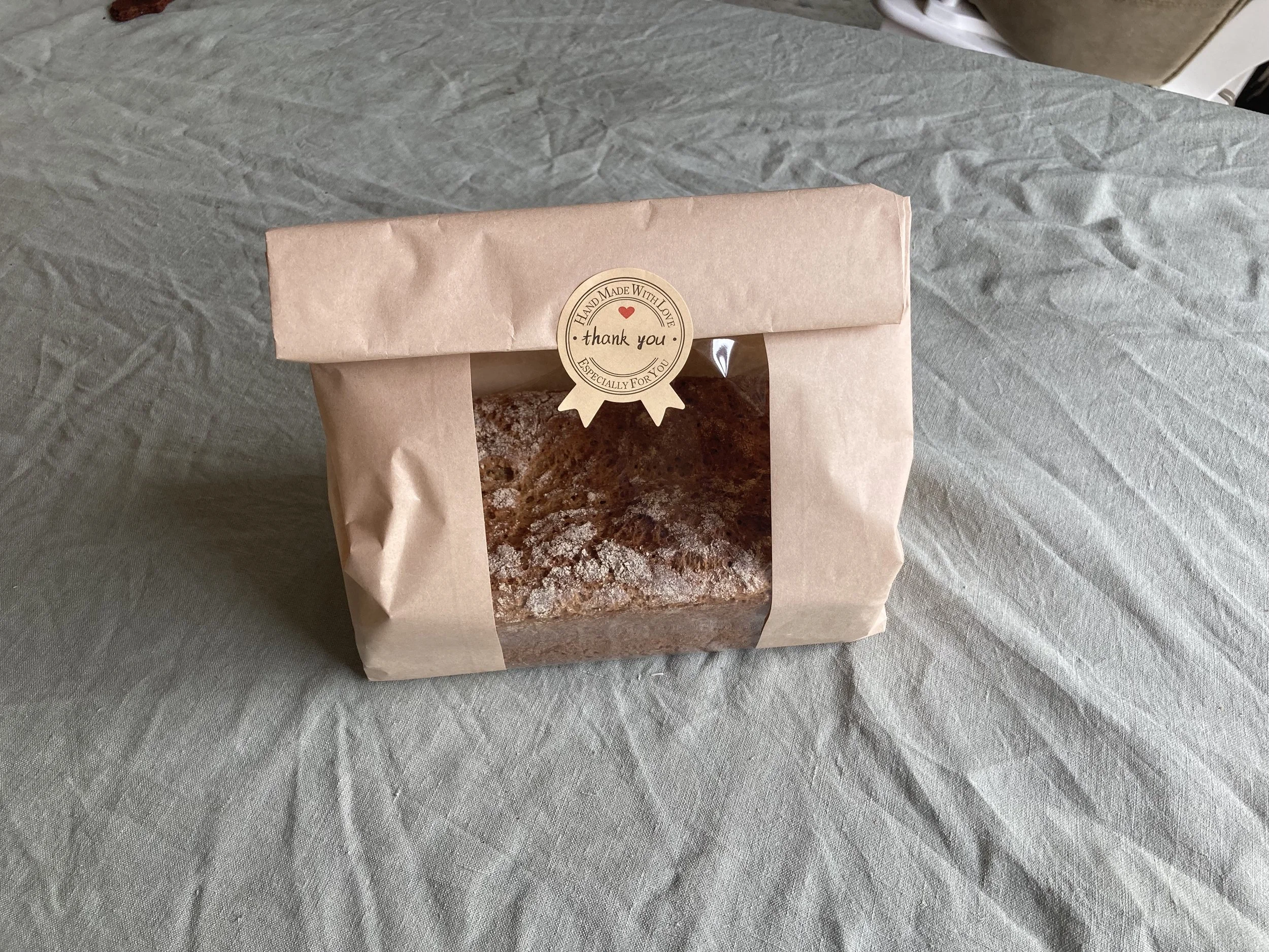 A paper bakery bag containing organic, fresh-milled einkorn bread loaf.