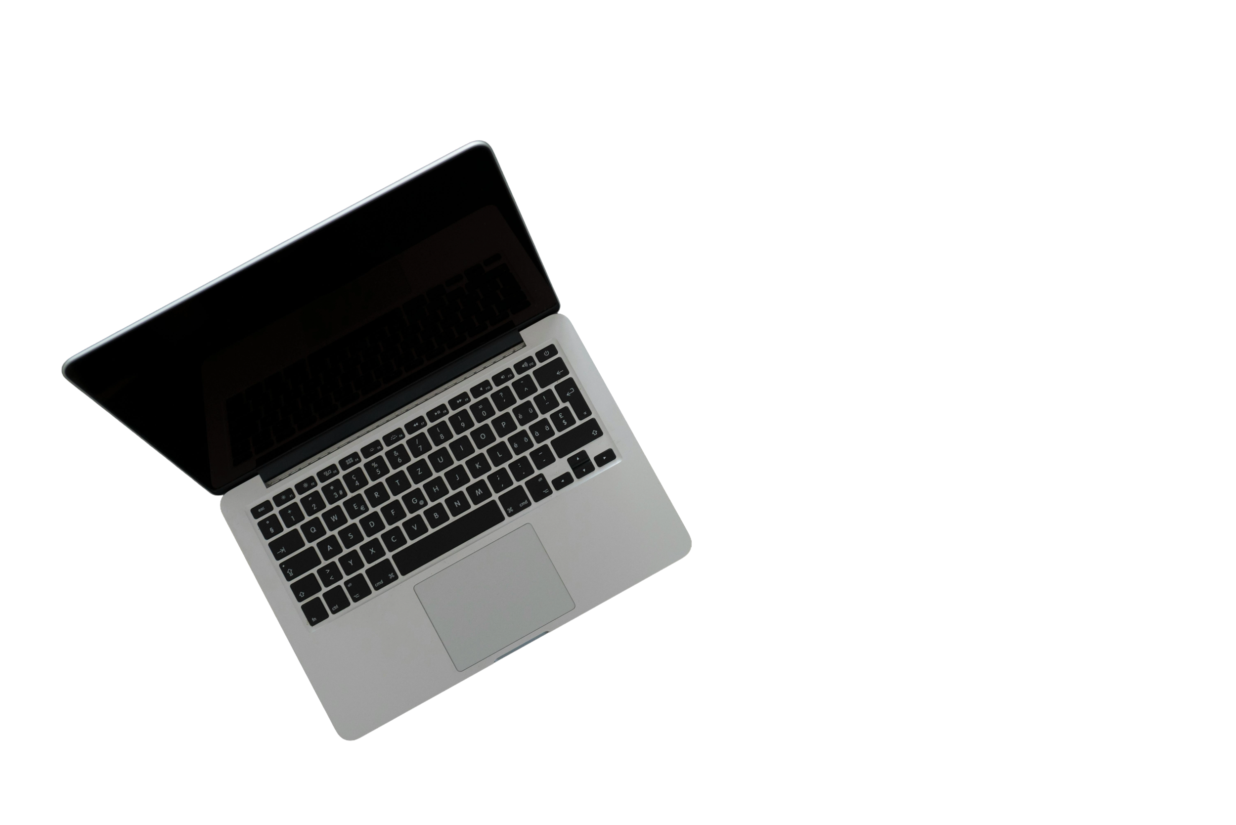 A silver laptop with a black keyboard is open on a black surface, showing the keyboard and partially the screen.