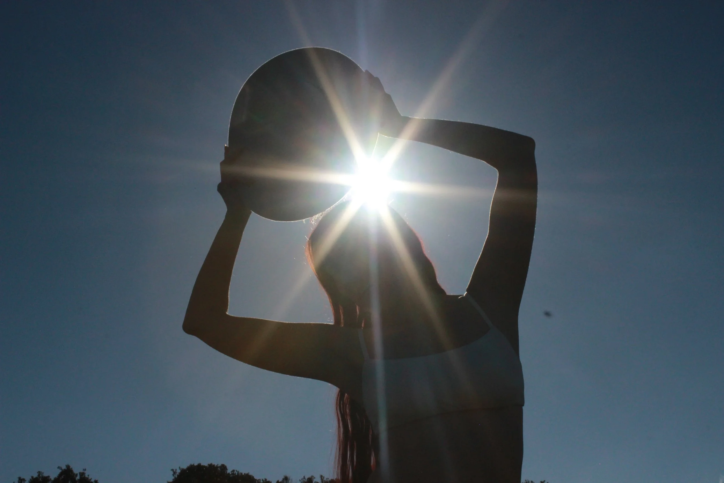 holding hat over head sun exploding behind sillhouette.JPG