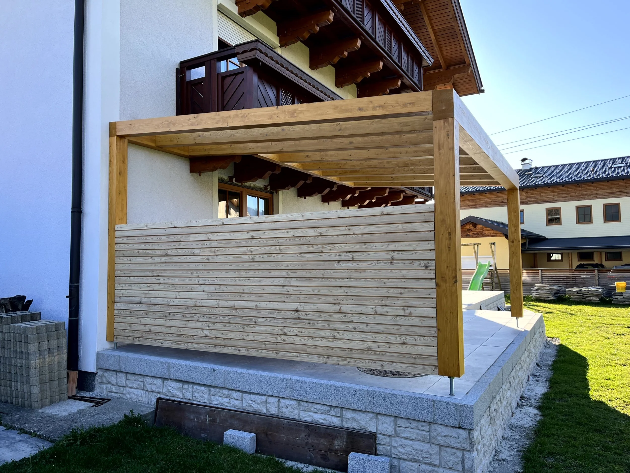 Terrassenüberdachung, Pergola mit seitlicher Holzverkleidung mit horizontalen Brettern. 