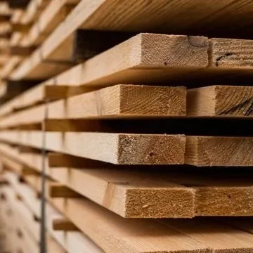 Holzplanken gestapelt in einem Lagerraum.