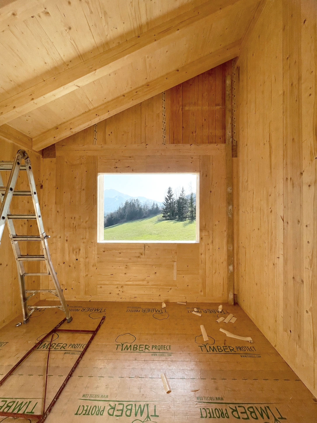 Innenraum eines noch im Bau befindlichen Holzhauses mit Fenster.