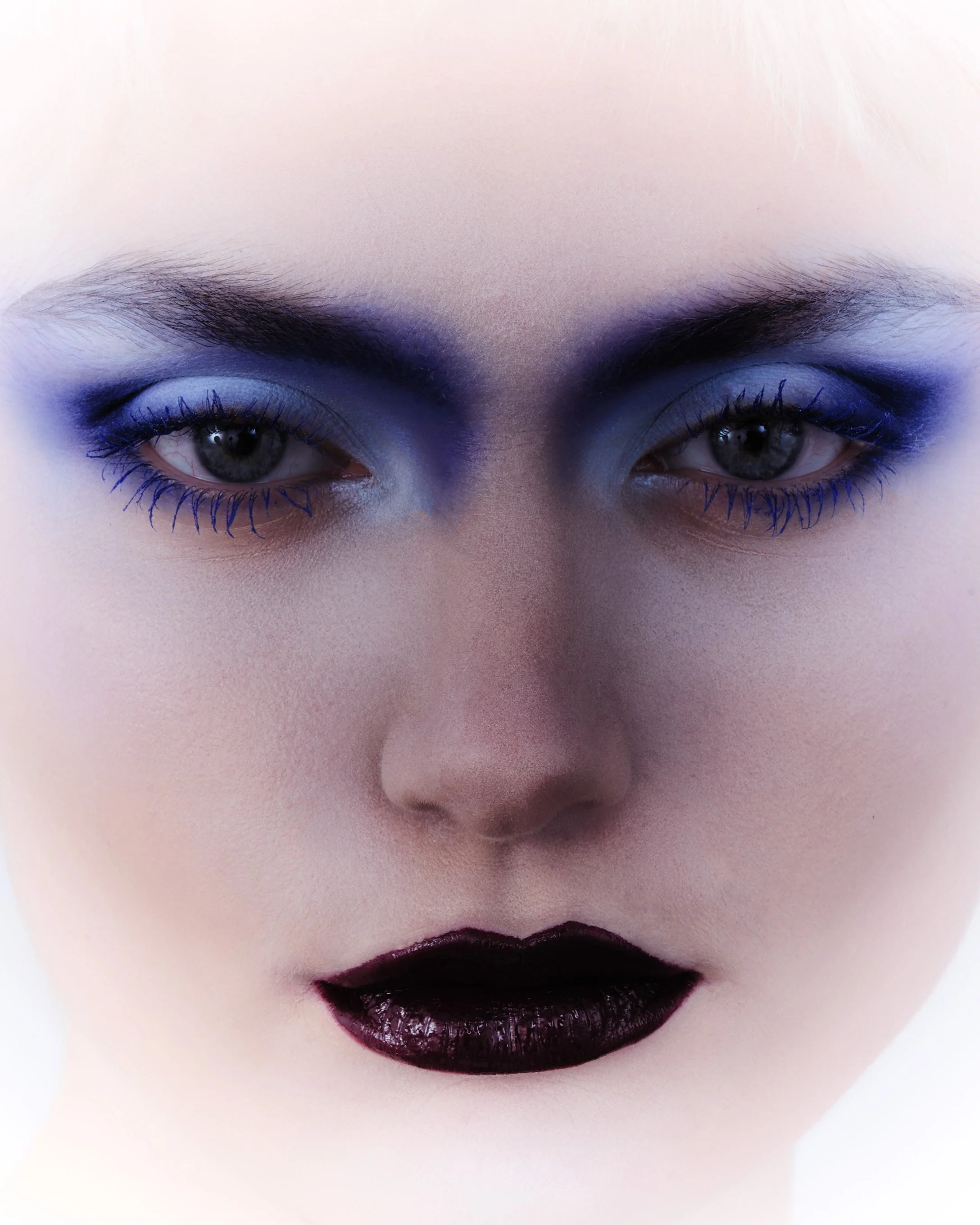 Close-up of a person's face with makeup, including bold dark lipstick and eye makeup, and eyebrows.
