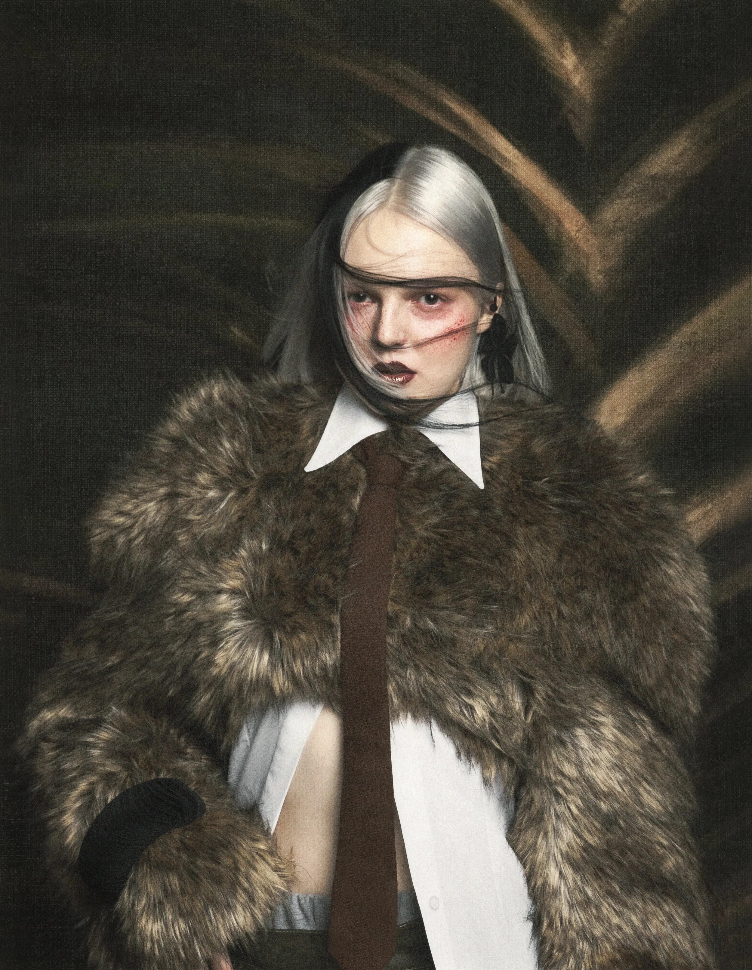Person with gray hair and makeup wearing a fur coat and a white shirt, holding a black-gloved hand with a palm up, in a dark setting with a wooden background.