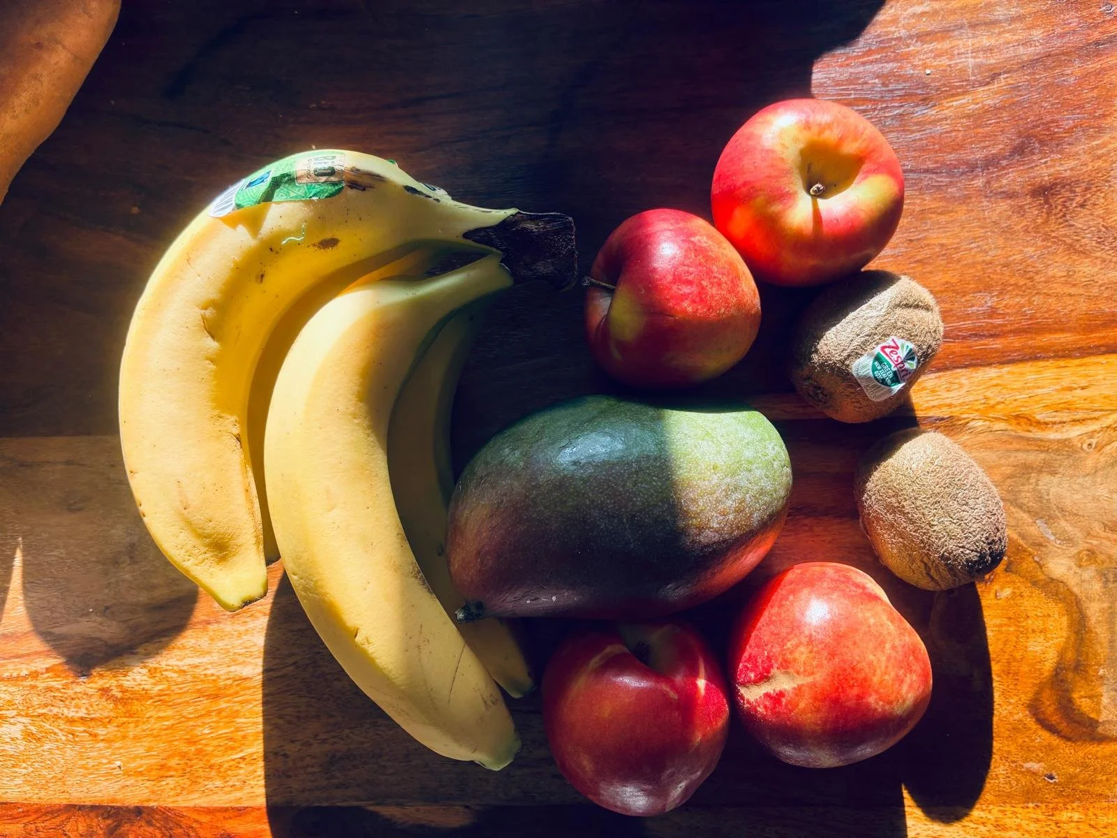 Fresh fruits from Lidl including bananas, mango, apples, kiwi, and nectarines on a wooden surface