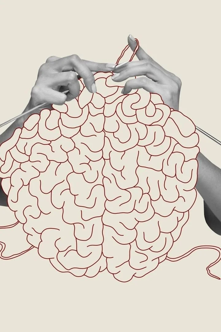 Hands knitting a brain-shaped object with red yarn, with the brain outline drawn in red lines.