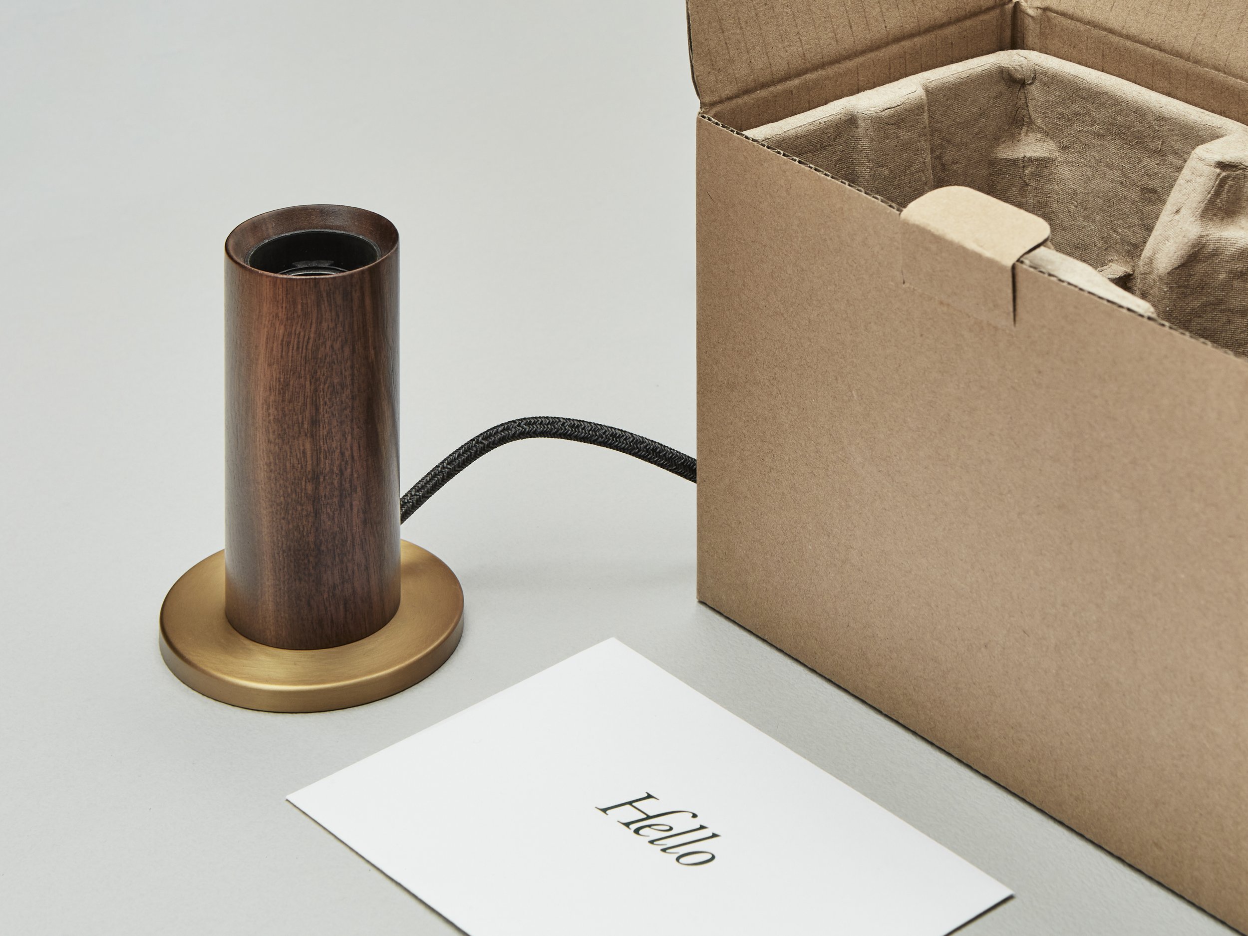Close-up view of a Tala lamp wooden base and a branded note card reading: Hello.