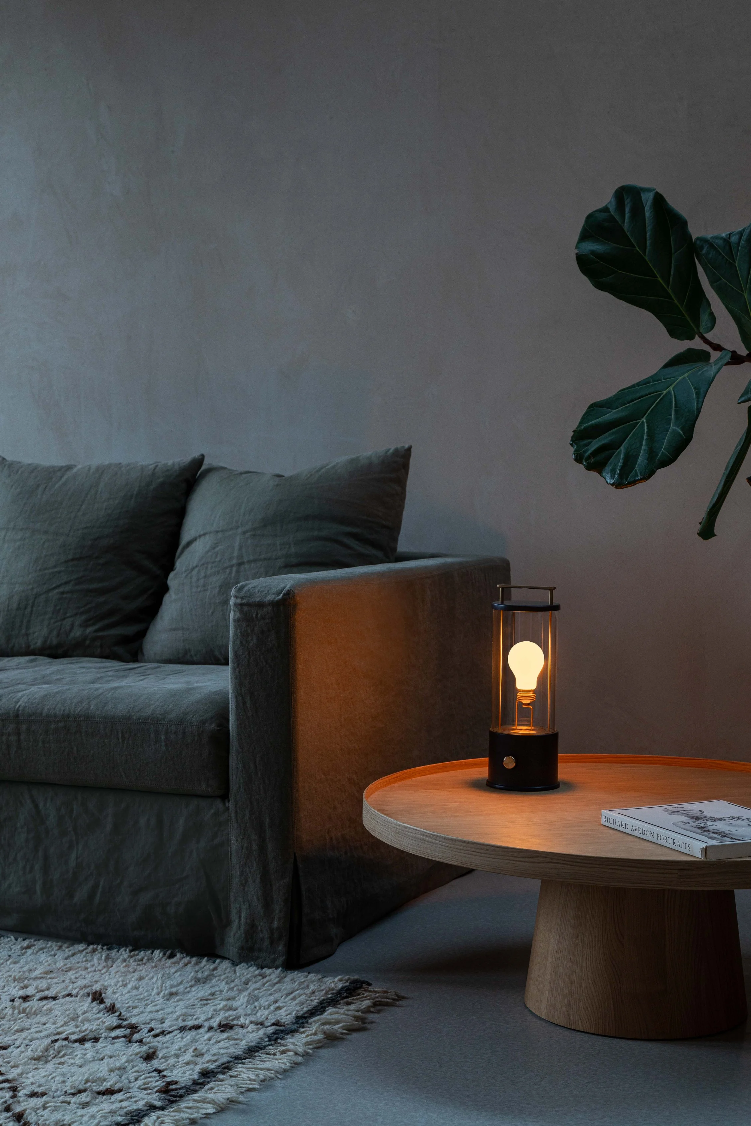 Minimalist living room at night featuring a Tala portable cordless lamp on a wooden side table.