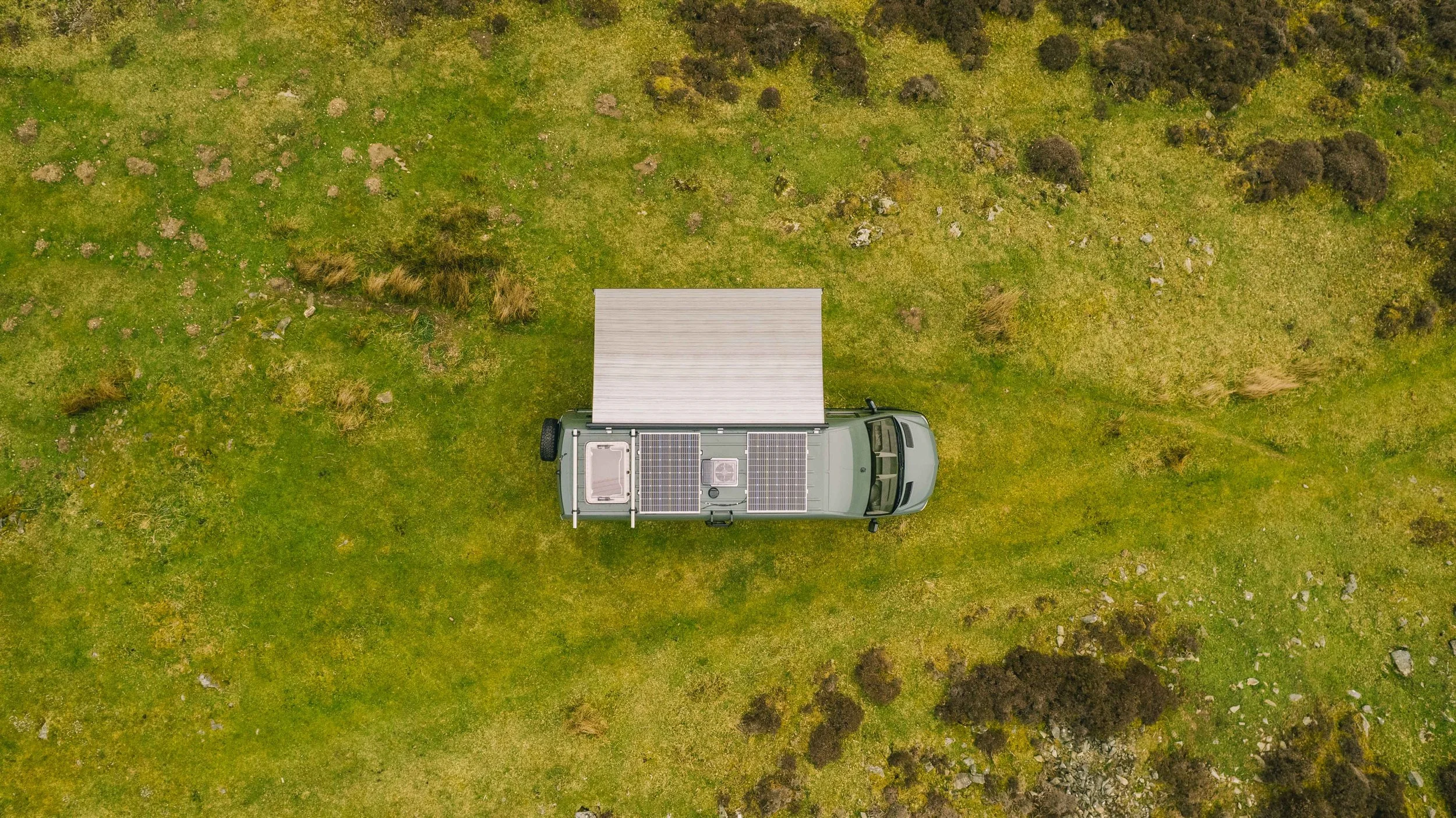 Aerial view of a Wingbeat Escapes camper van showing the roof solar panels and extended canopy.