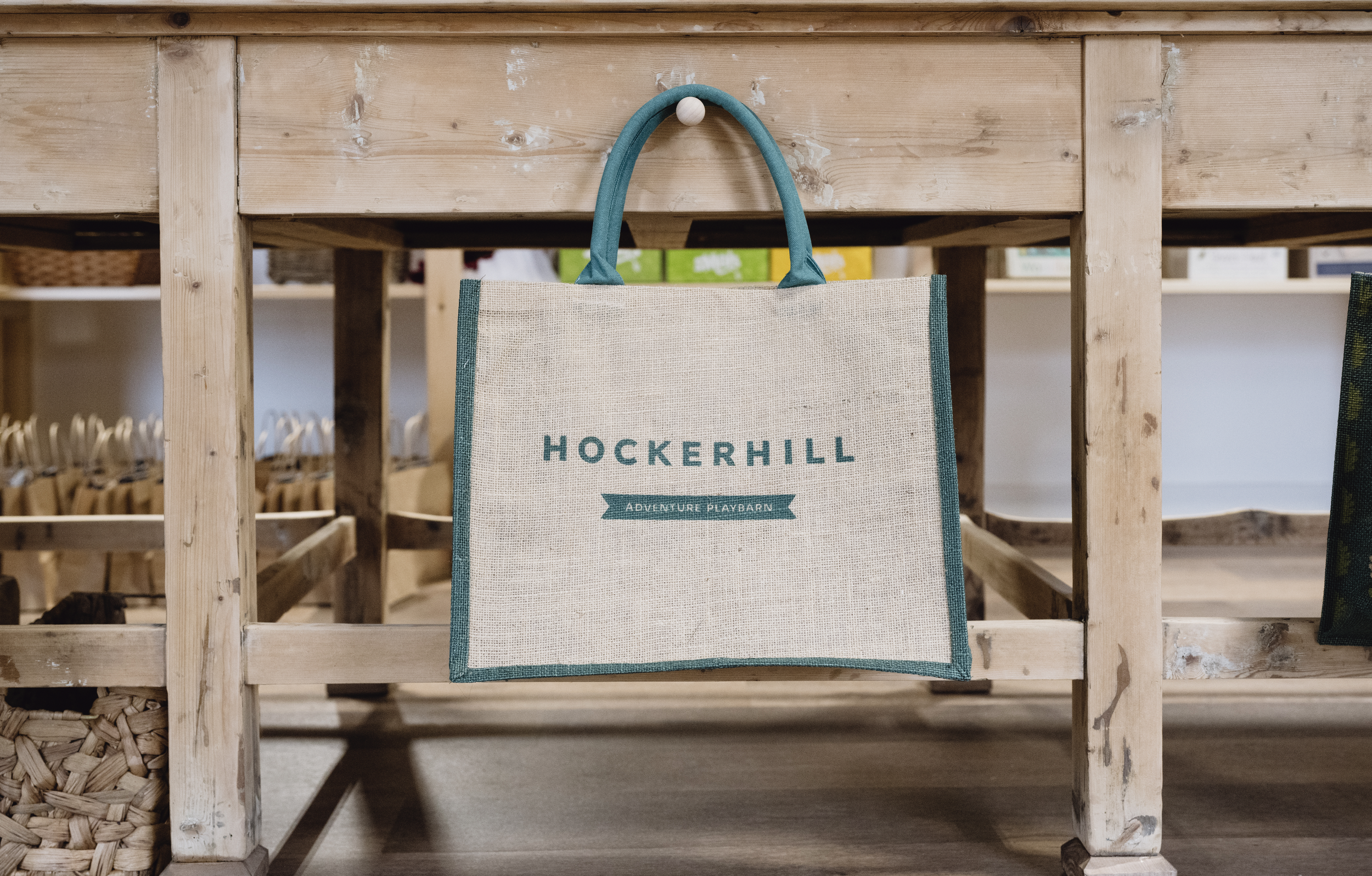 A premium branded jute tote bag with dark green handles hanging on display in the Hockerhill shop.