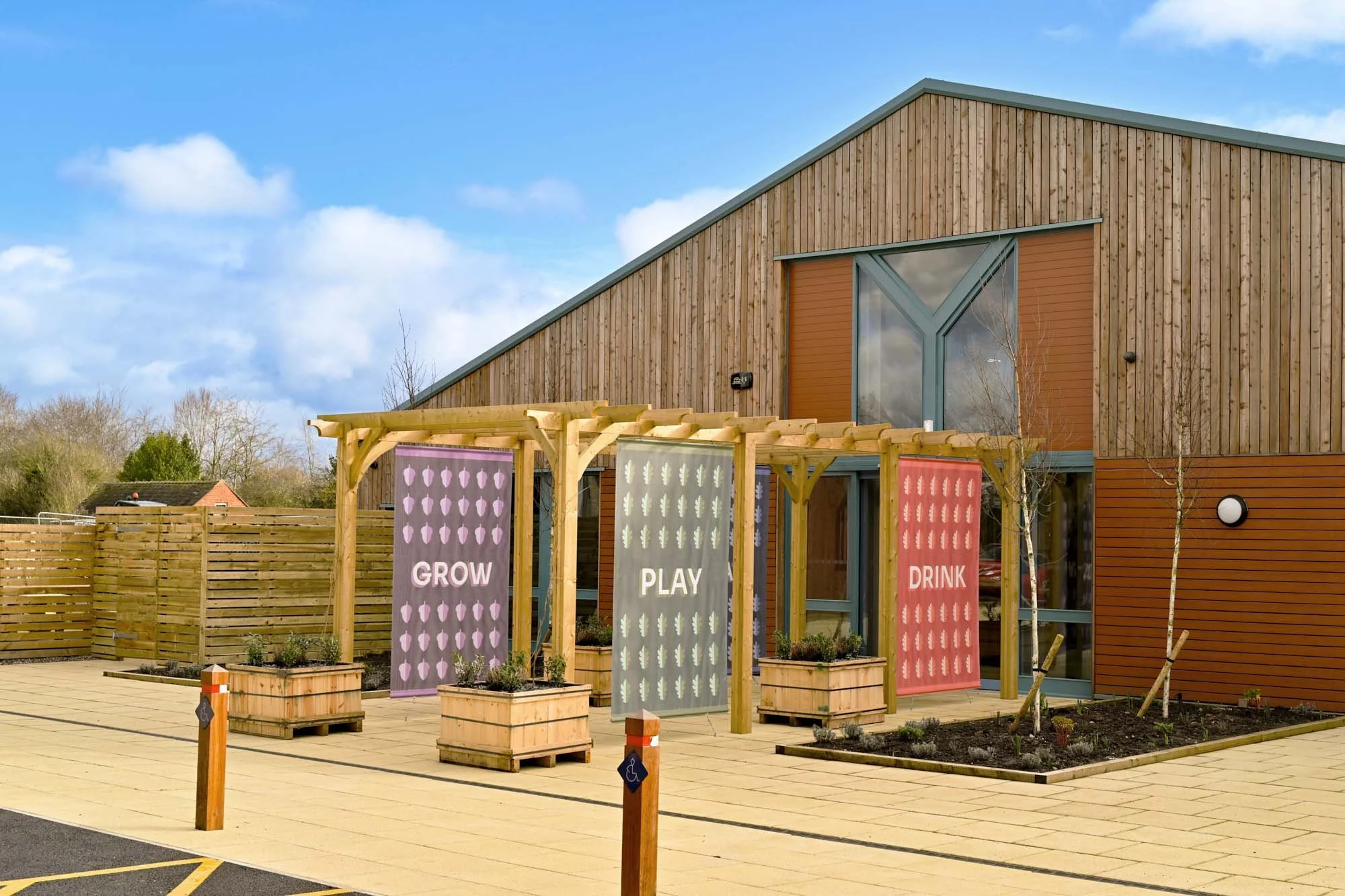 Front entrance of Hockerhill Adventure Playbarn decorated with bespoke brand-coloured pergola flags.