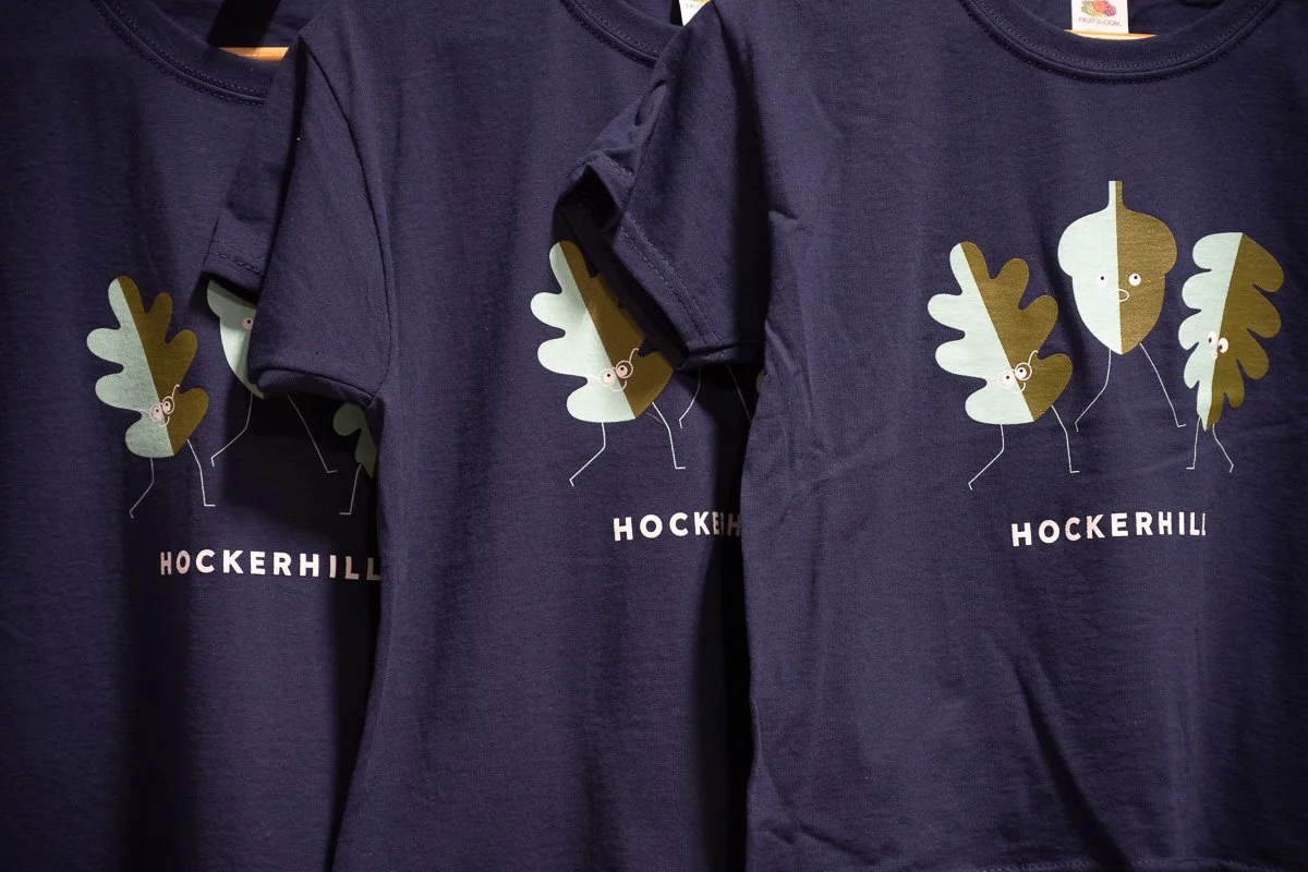 Close-up of Hockerhill children's t-shirts printed with three illustrated character assets and the logo.