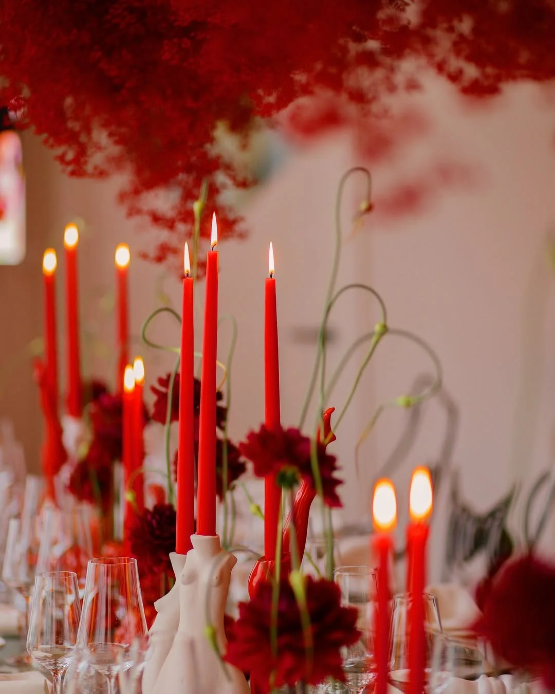 An exquisitely set table at a Pomelo event, adorned with crimson candles, matching florals, and hanging blooms.