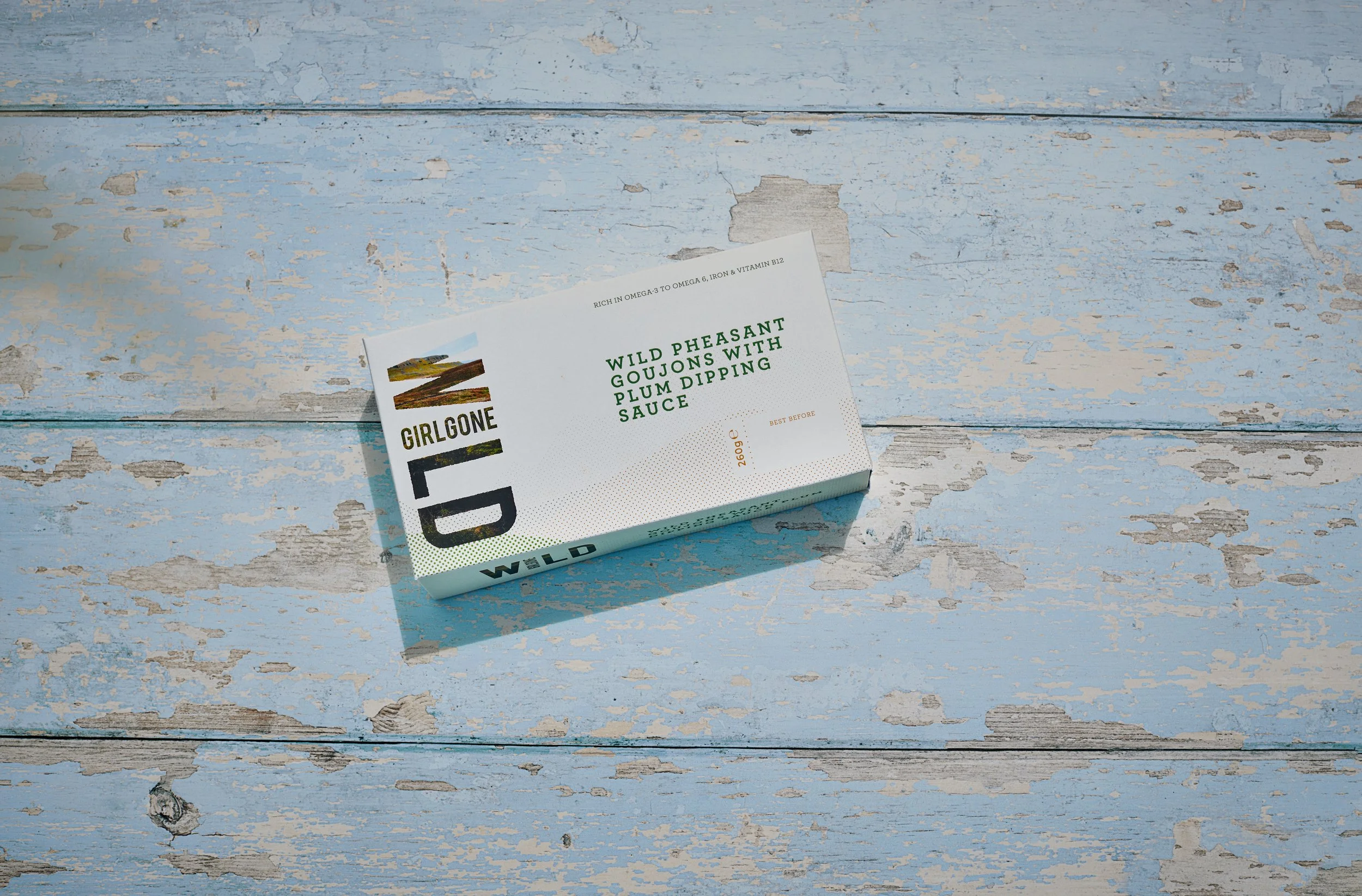 A Girl Gone Wild Pheasant Goujons product pack resting on a rustic, light blue painted wooden table.