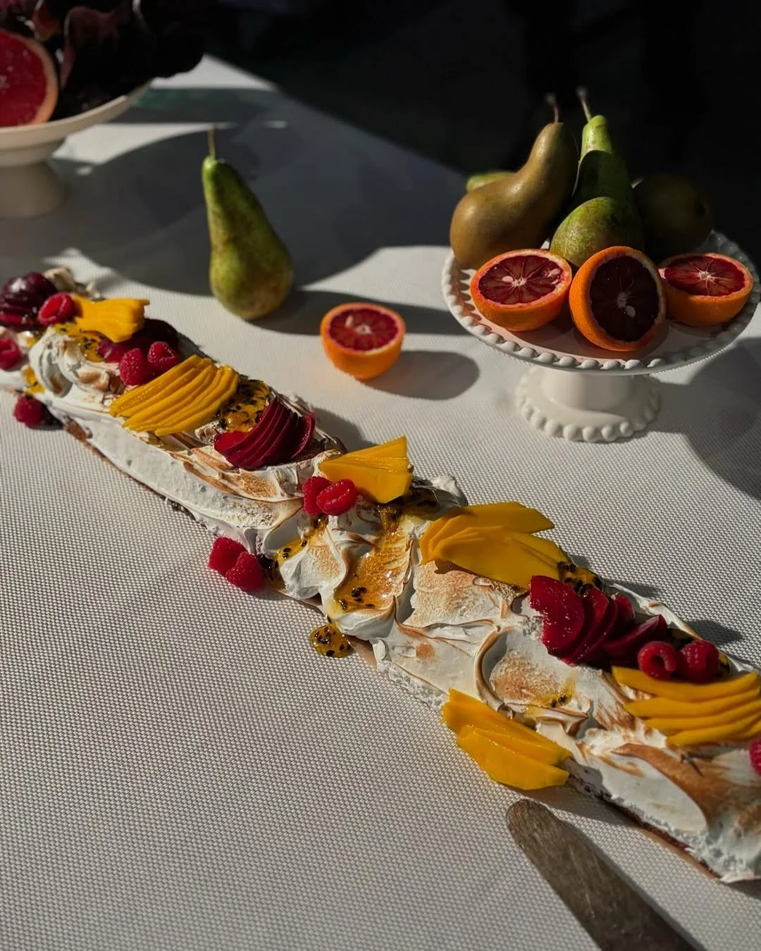 Vibrant Pomelo catering table setting featuring a summer pavlova with fresh fruit.