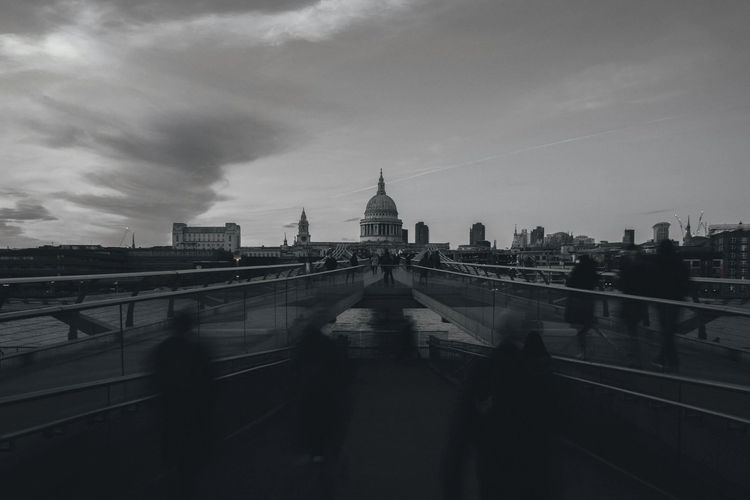 Black and white photograph of London's Millennium Bridge leading toward St Paul's Cathedral on an overcast day.