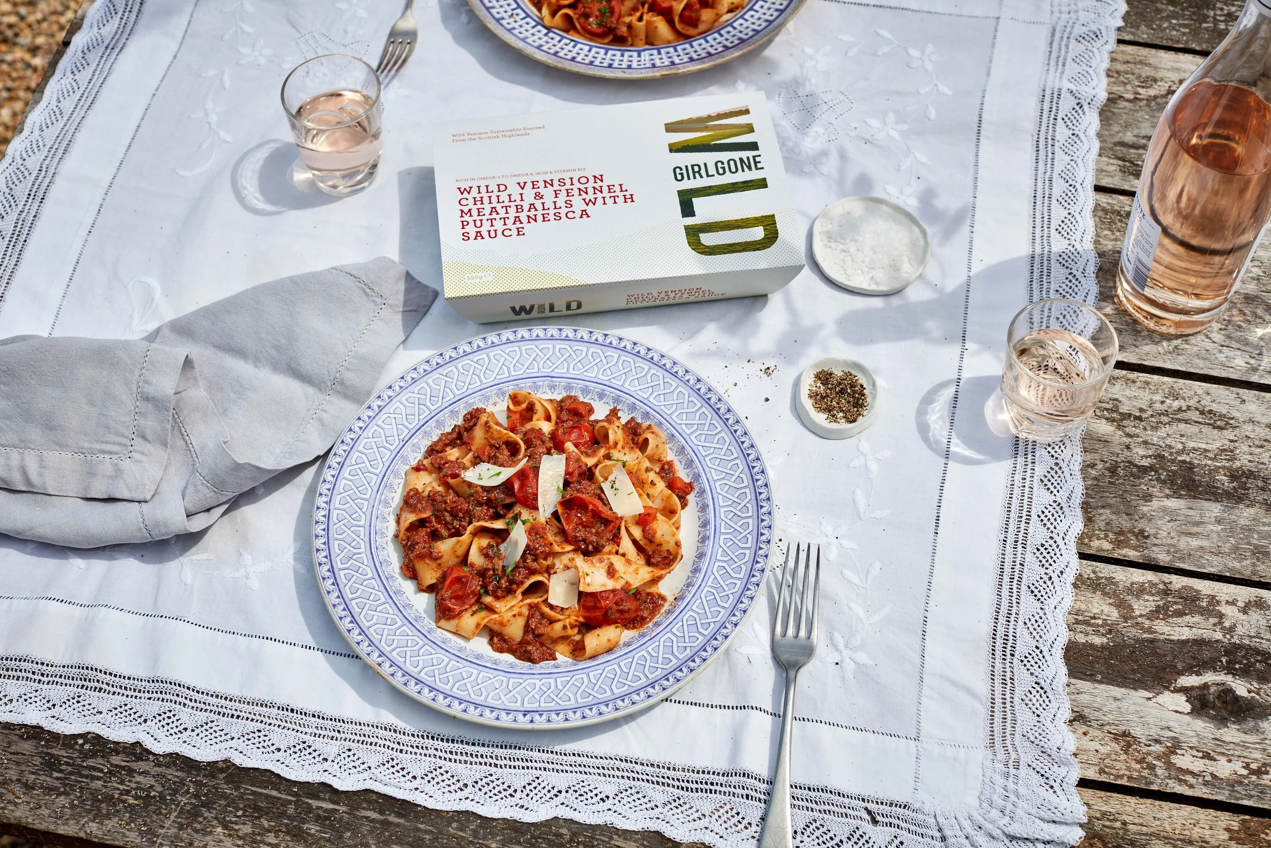 Wild venison meatballs served on a styled table with glasses of rosé and artisanal salt and pepper dishes.
