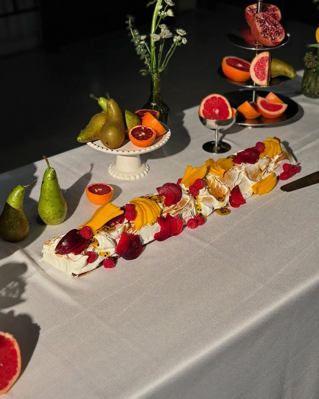 Vibrant Pomelo catering table setting featuring a summer pavlova with fresh fruit.