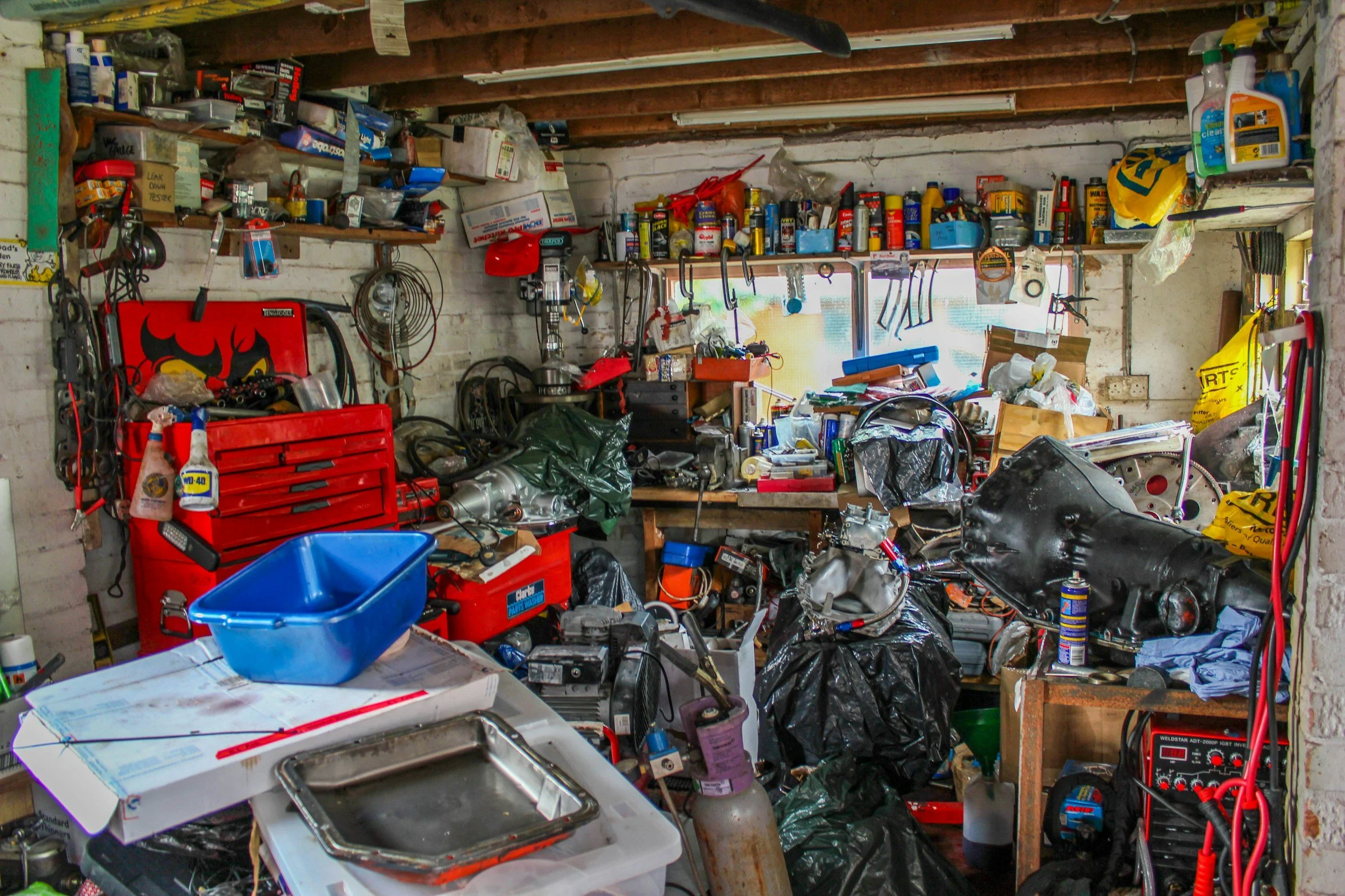 A cluttered and disorganized home workshop and garage in need of professional decluttering and rubbish removal services.