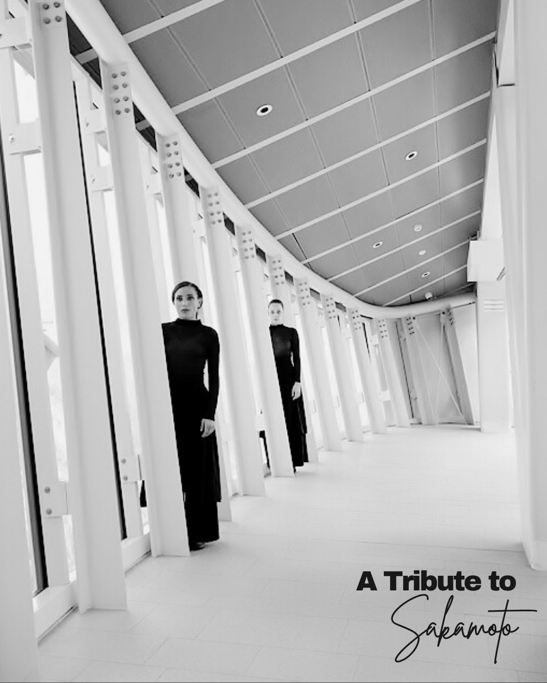 Black and white photo of a modern architectural interior with two women standing in a curved corridor, wearing black dresses, with the text 'A Tribute to Sakamoto' in the bottom right corner.