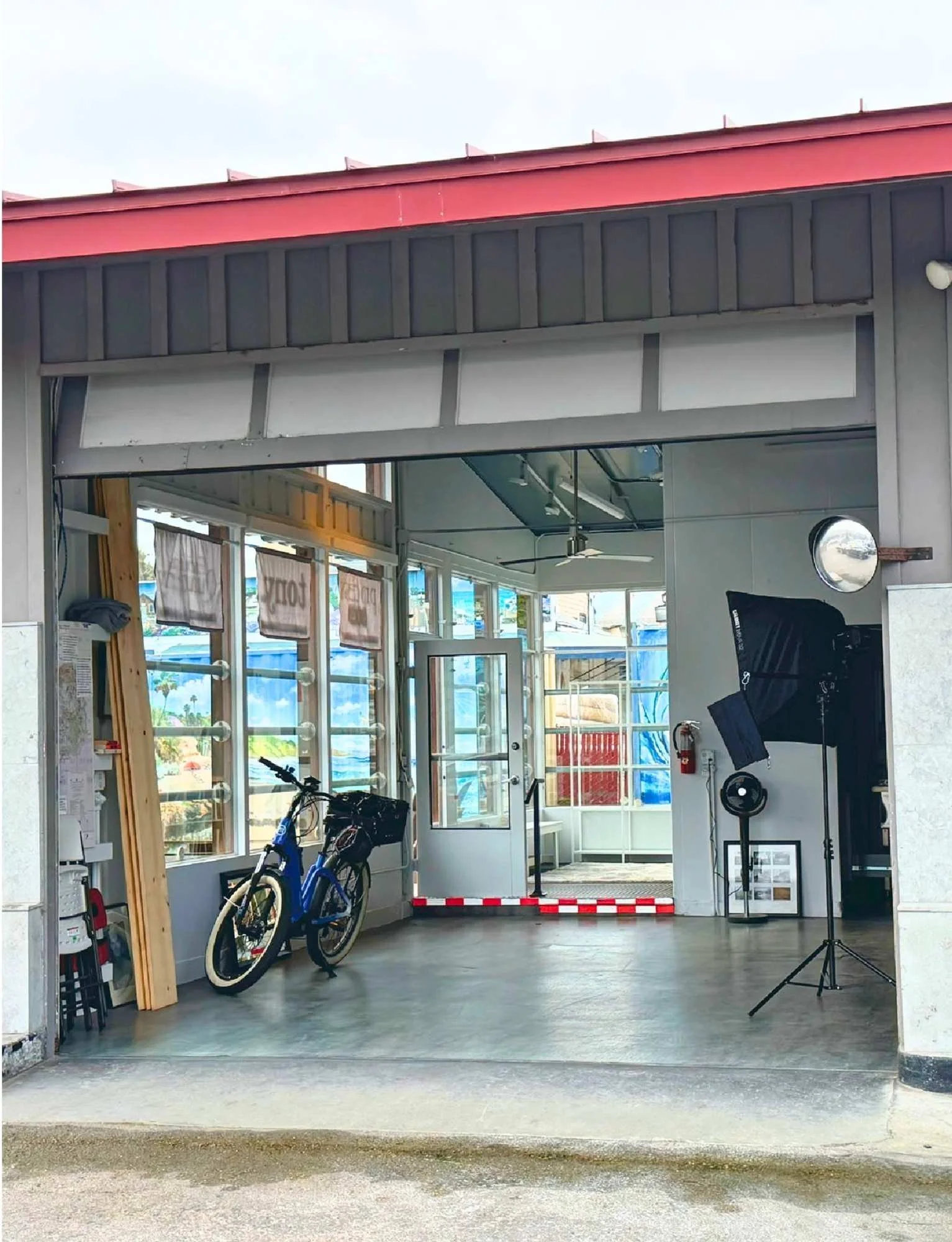 Modern storefront interior with large windows, a blue bicycle, and an open glass door.