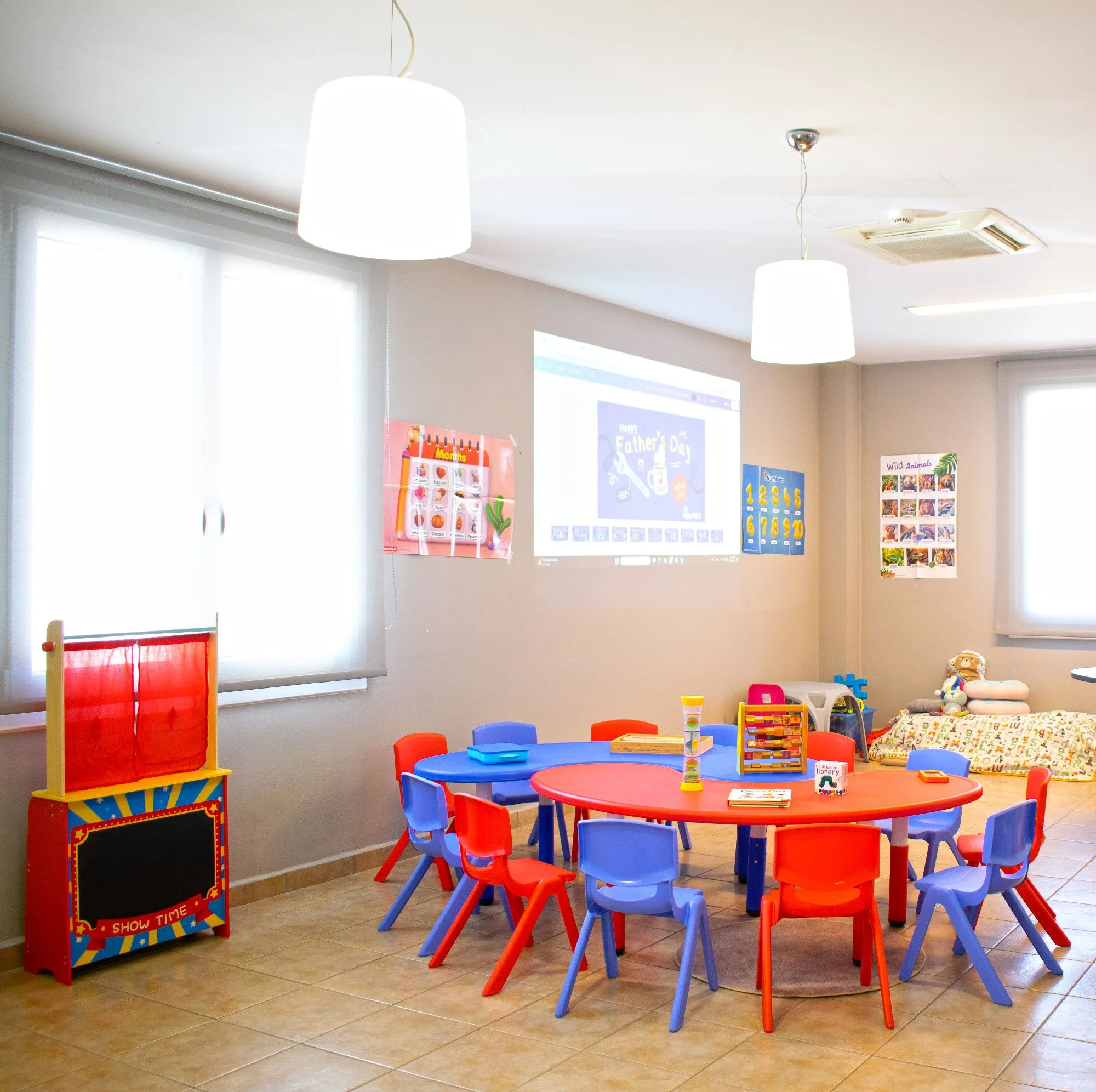 Bright classroom at Hello Bridge Academy with colourful tables, chairs, learning materials, and a projector for language lessons.