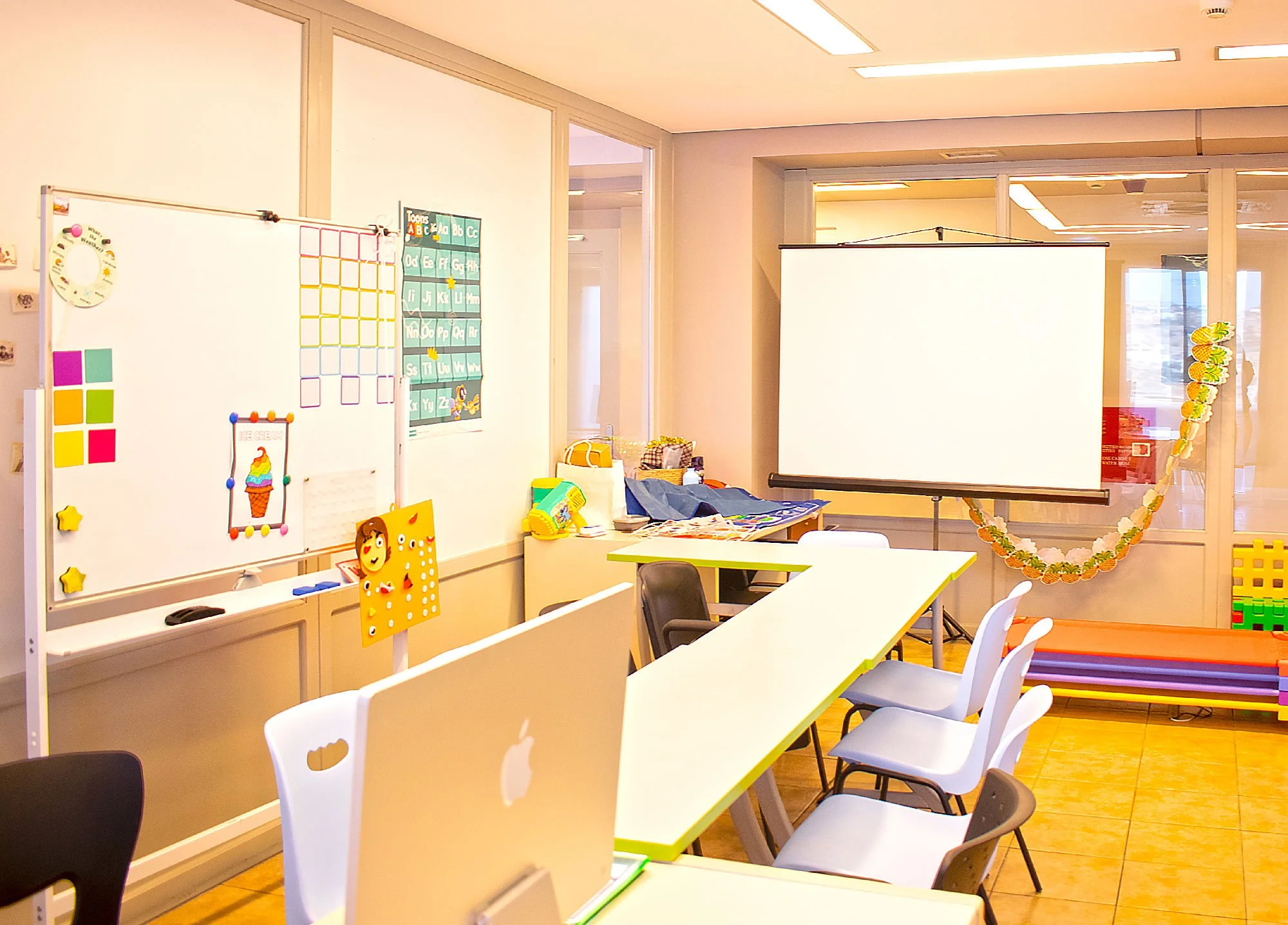 Bright classroom at Hello Bridge Academy with whiteboard, learning materials, projector screen, and colourful seating for language lessons.