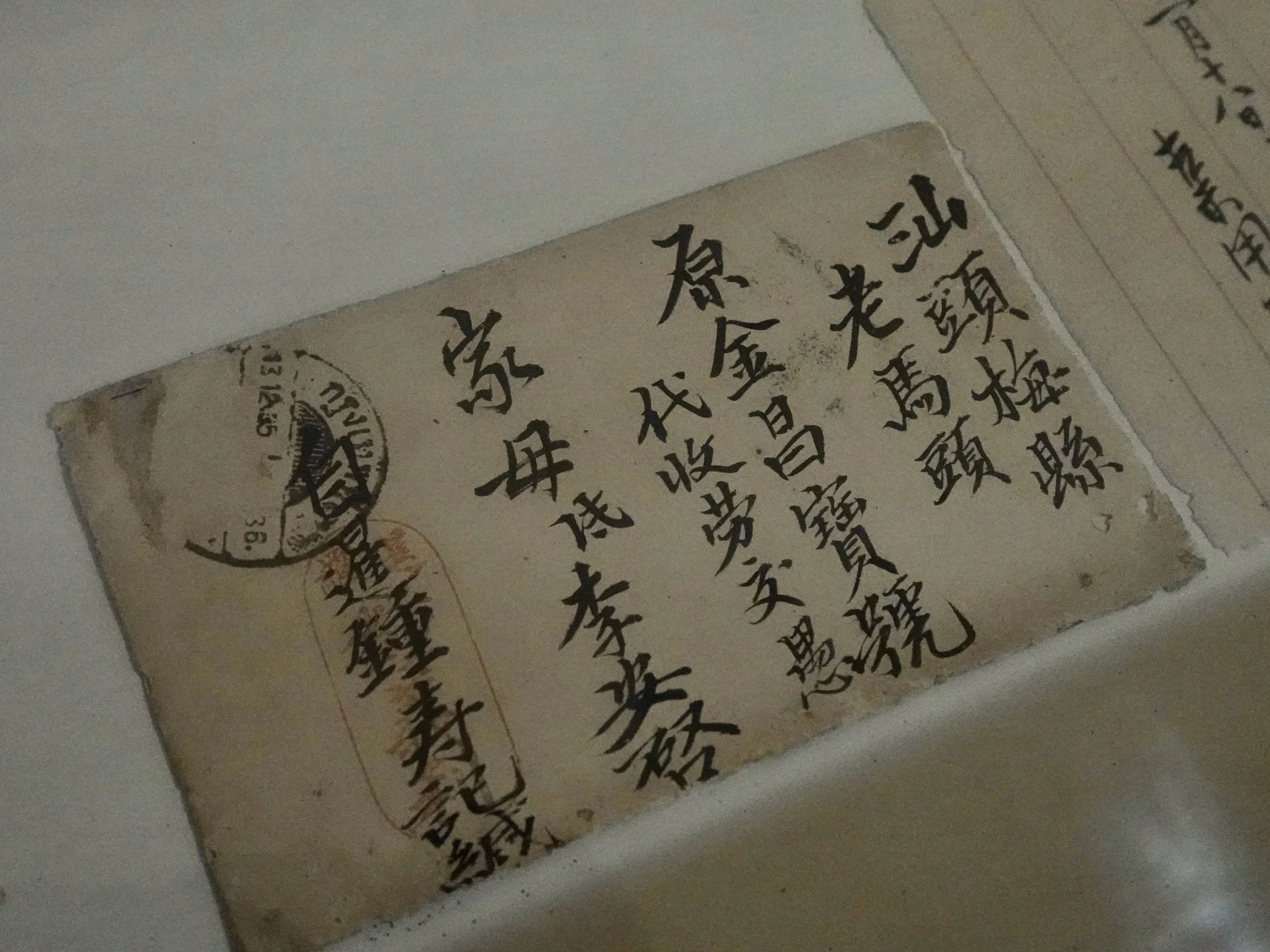 A handwritten Chinese envelope displayed at Songjiang Hotel, with vertical lines of calligraphy, postal marks and the characters 家母, addressing the sender’s mother.