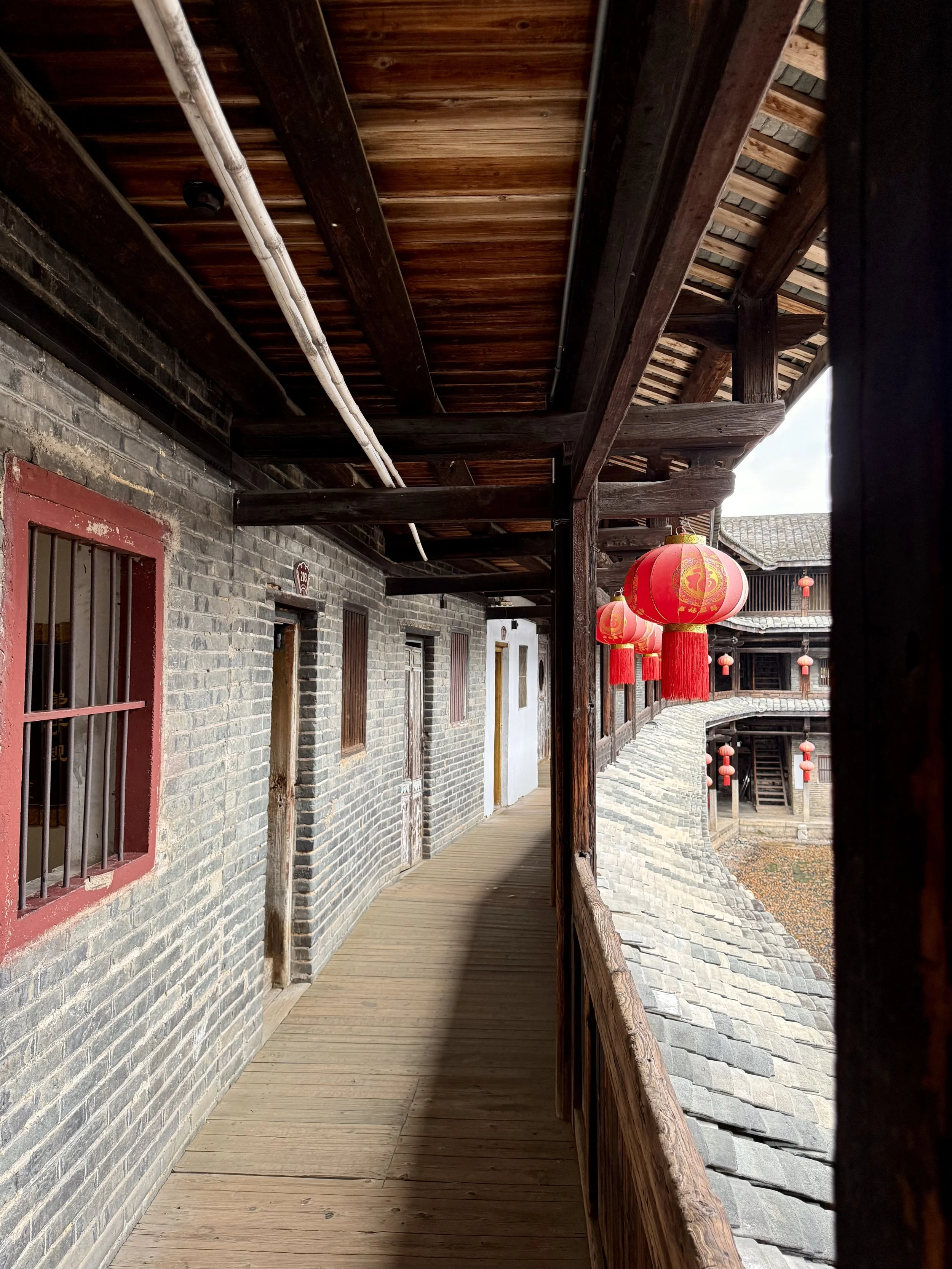 Upper timber gallery inside Tai’an Lou, with repeated doors and railings overlooking the internal compound.