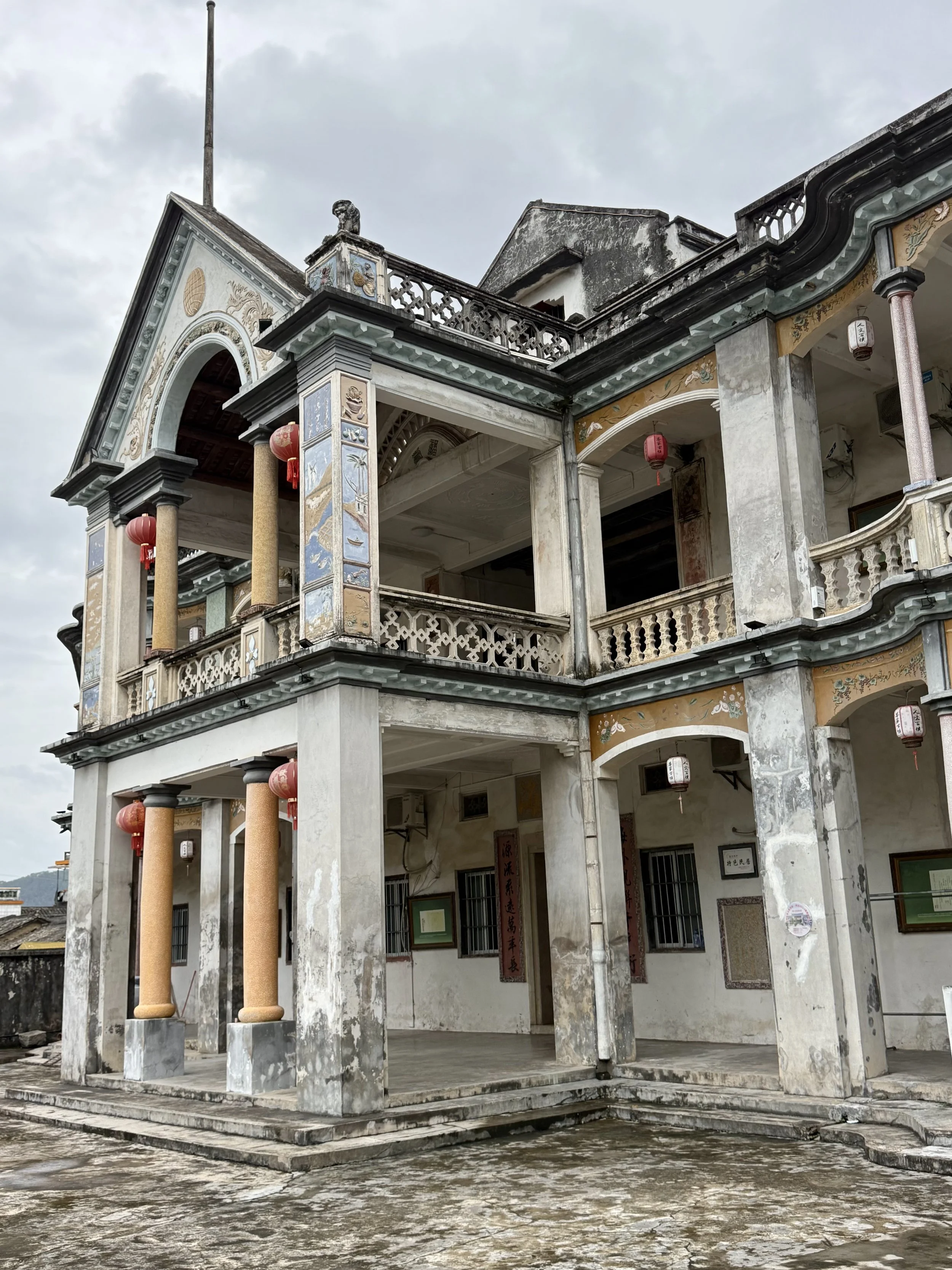 Exterior of Haiyuan Lou in Baihou with three-storey balconies, arches, columns, balustrades and painted decorative panels.