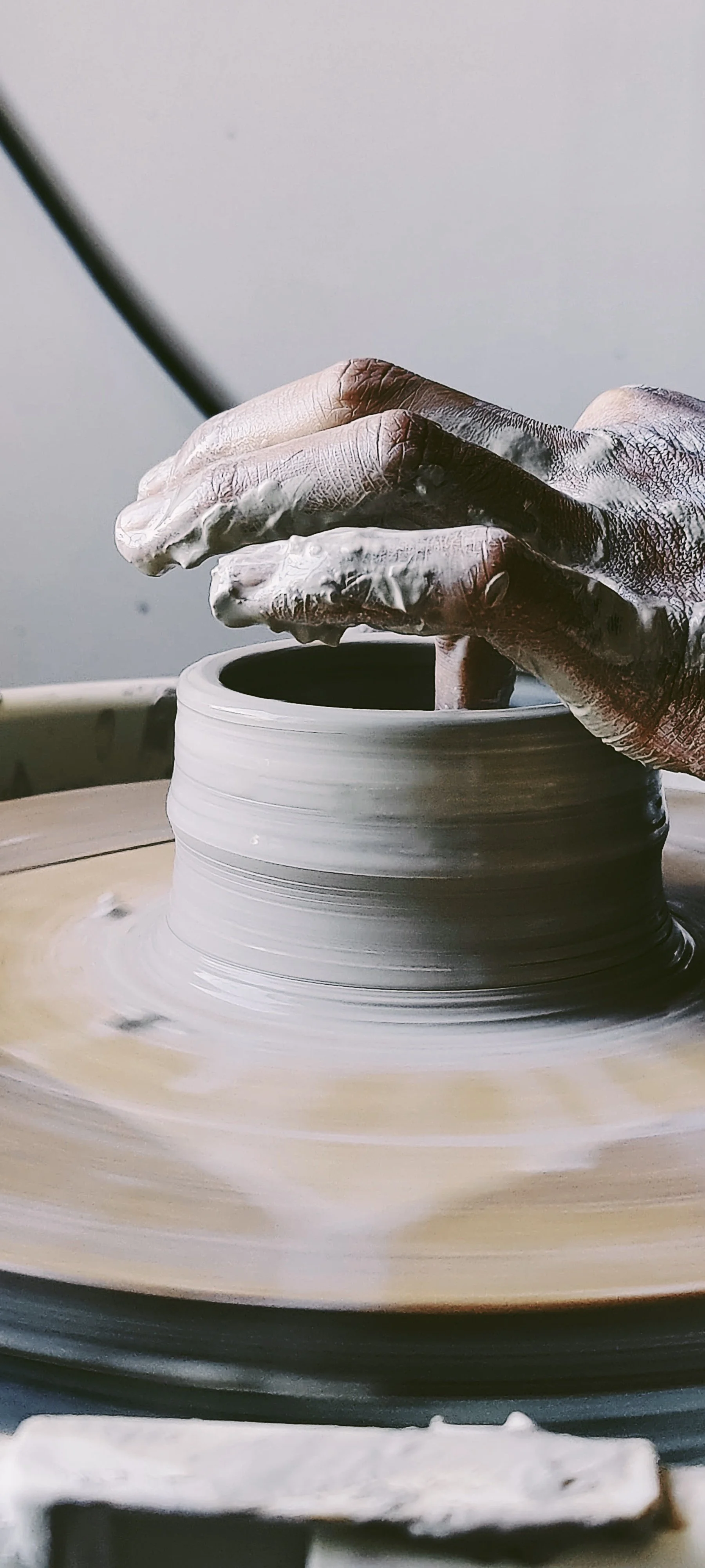 Hands shaping clay on the wheel