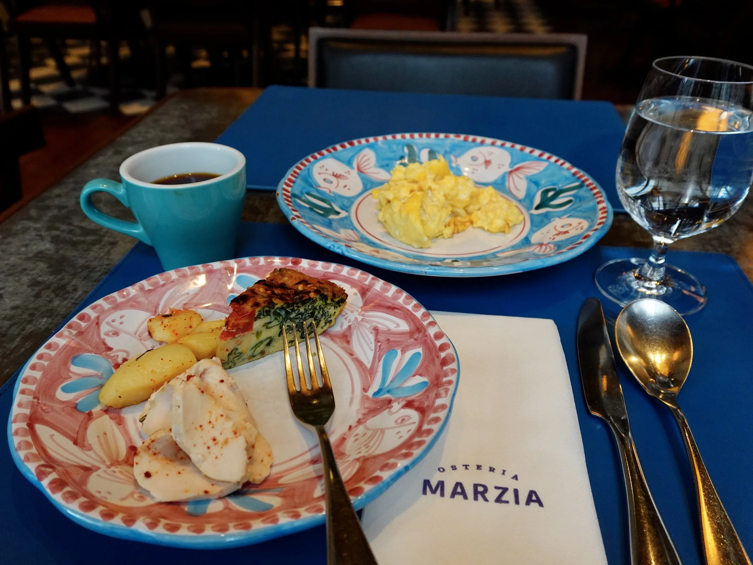 Breakfast of eggs, frittata and roasted potatoes served on colourful ceramic tableware at Osteria Marzia