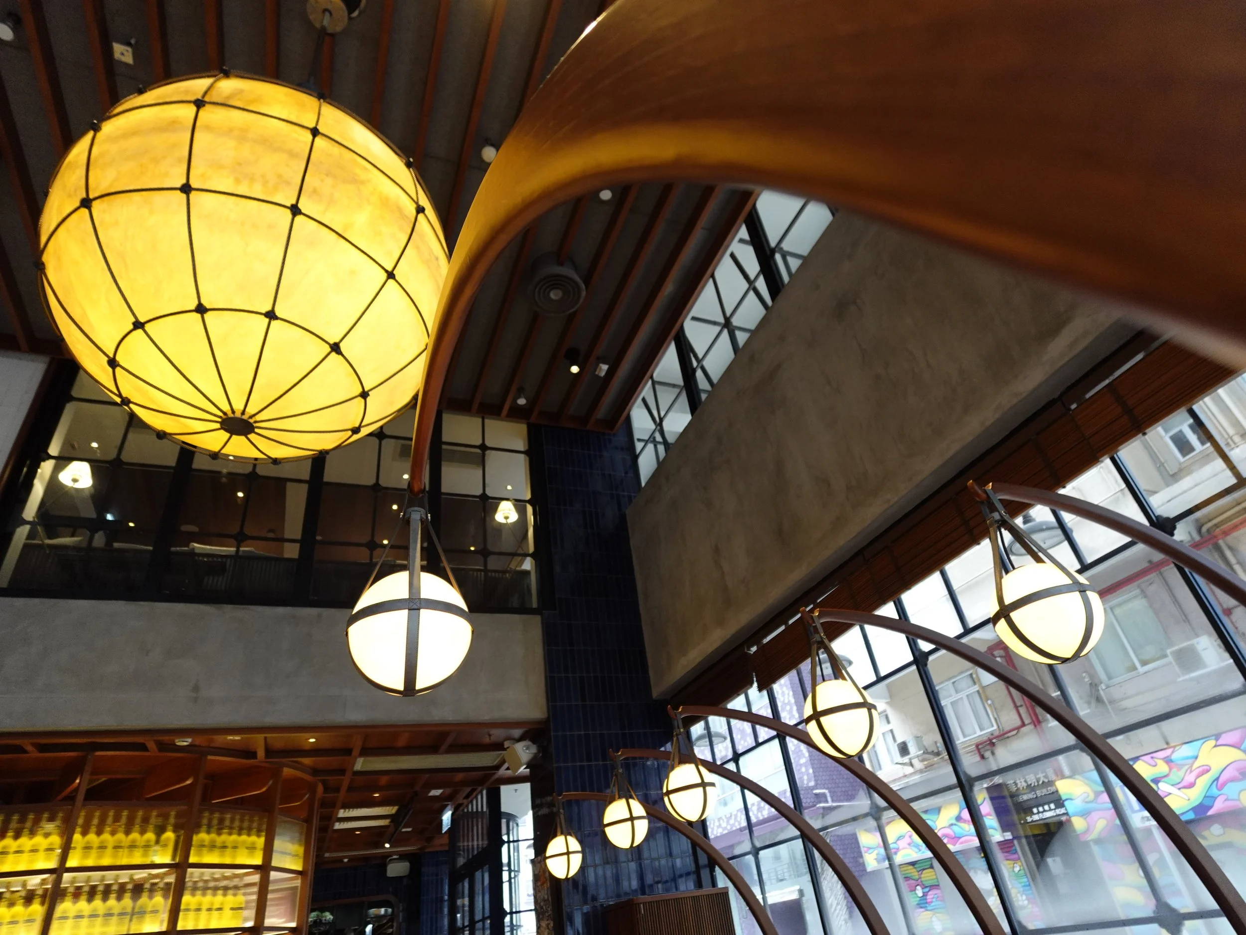 Interior of Osteria Marzia with large spherical fishing-lantern-inspired lights and curved timber supports