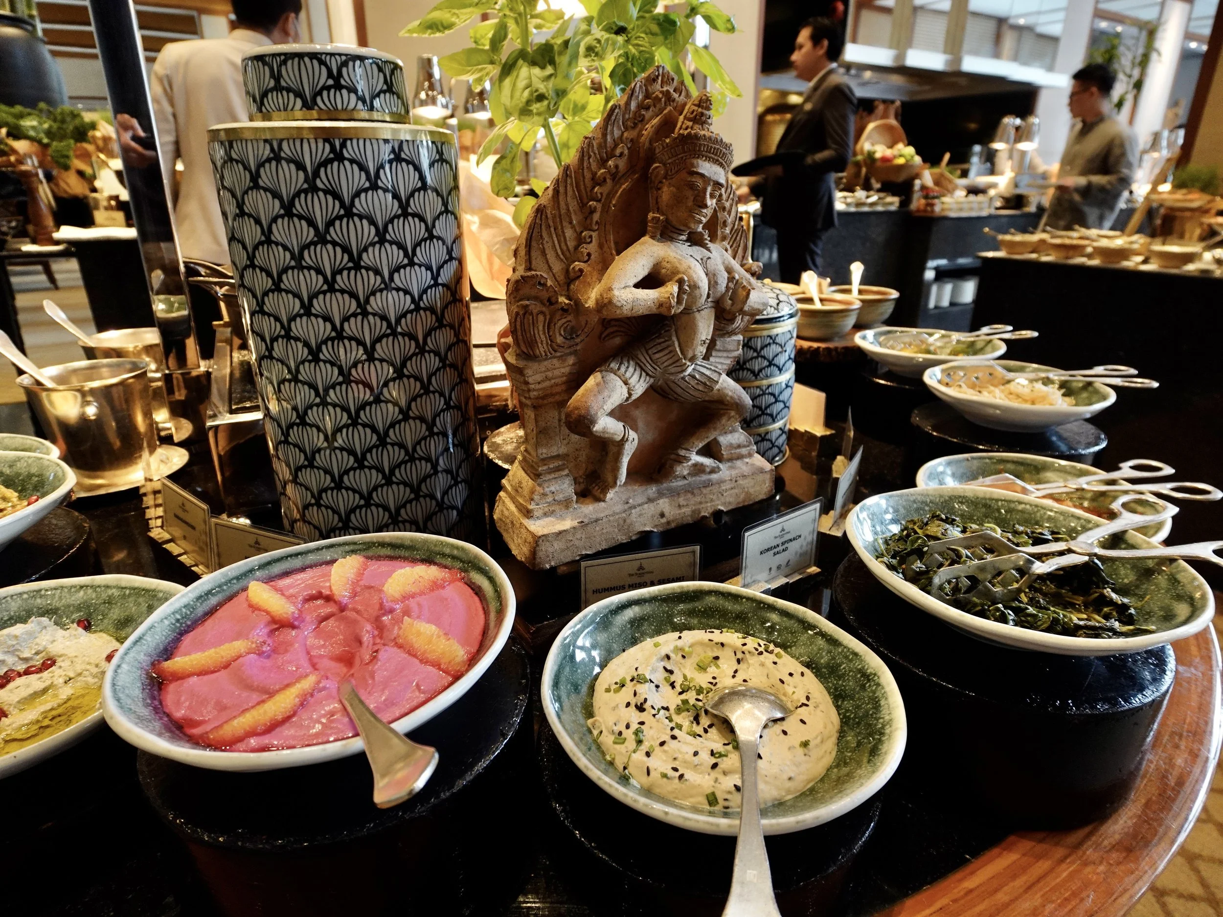 Breakfast dishes are arranged around blue-and-white ceramics and a decorative sculpture at The Sukhothai Bangkok.