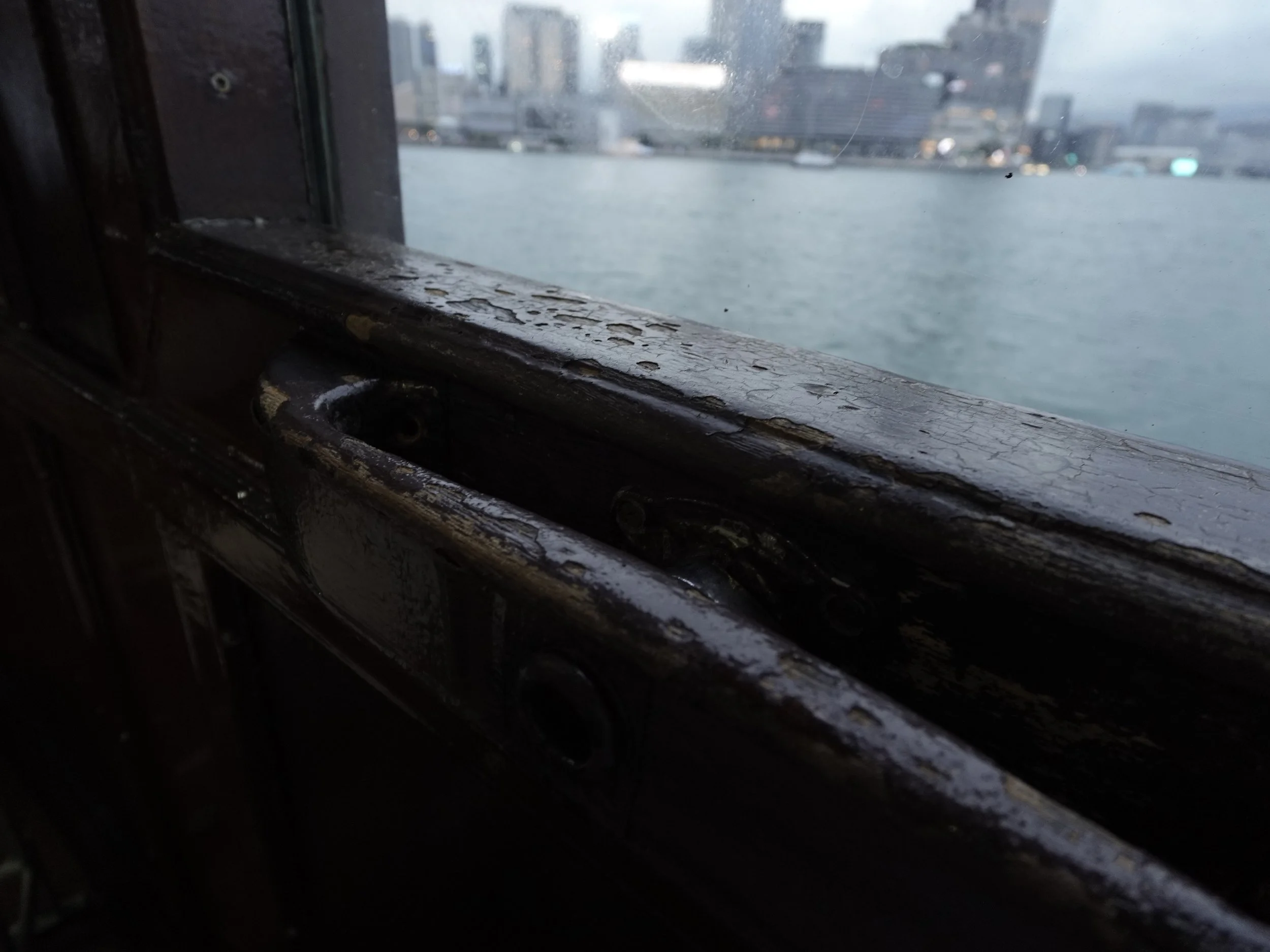 Worn timber window frame inside a Star Ferry with Victoria Harbour visible beyond