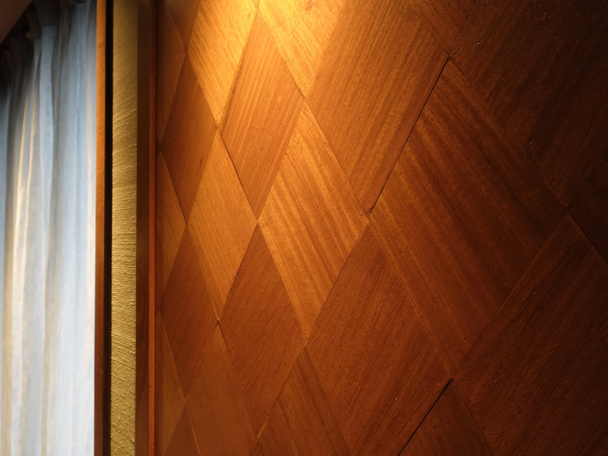 Diamond-shaped sections of warm wooden wall panelling form a repeating geometric pattern.