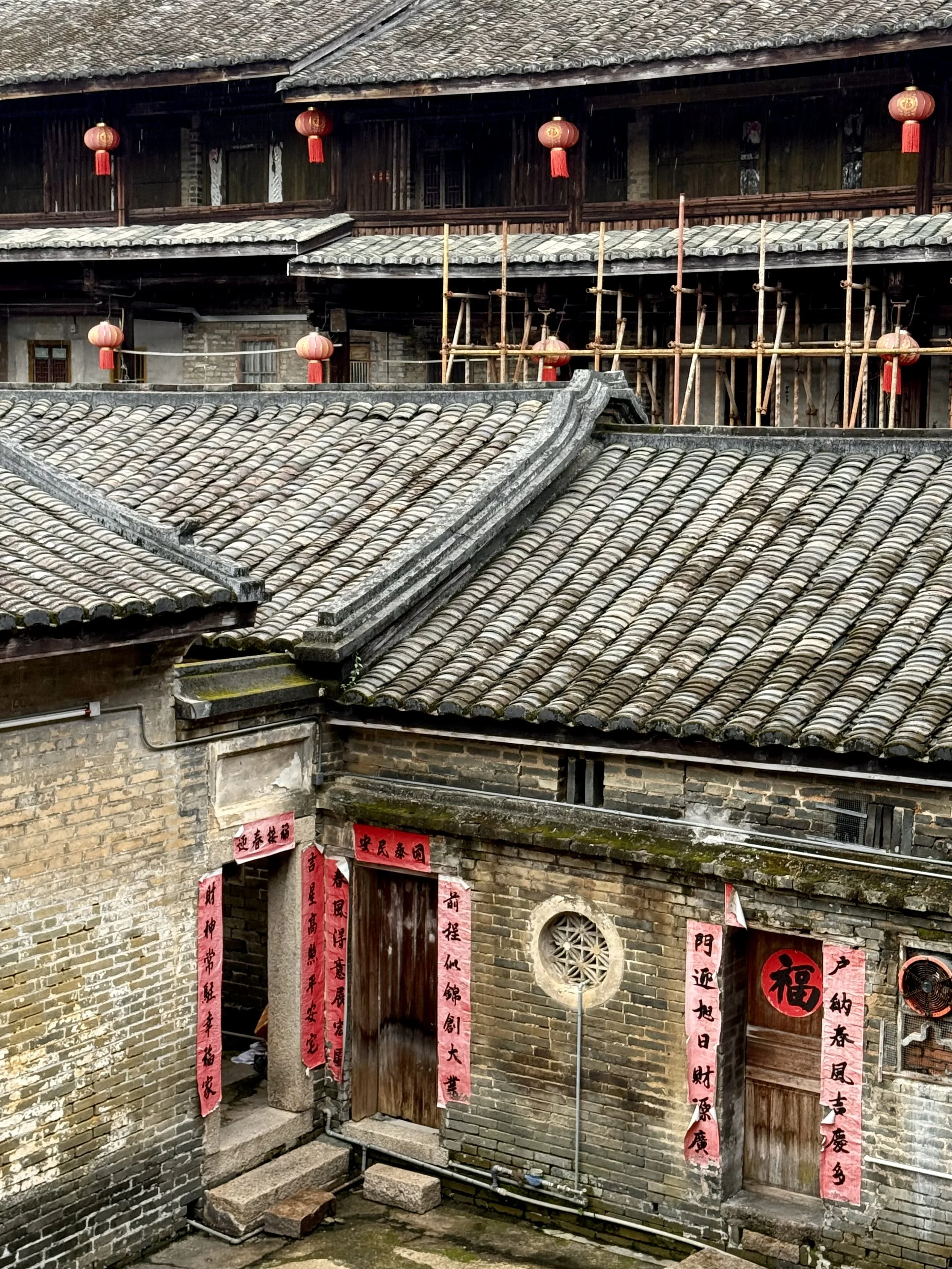 Overlapping tiled roofs and internal courtyards seen from an upper level of Tai’an Lou in Dabu.