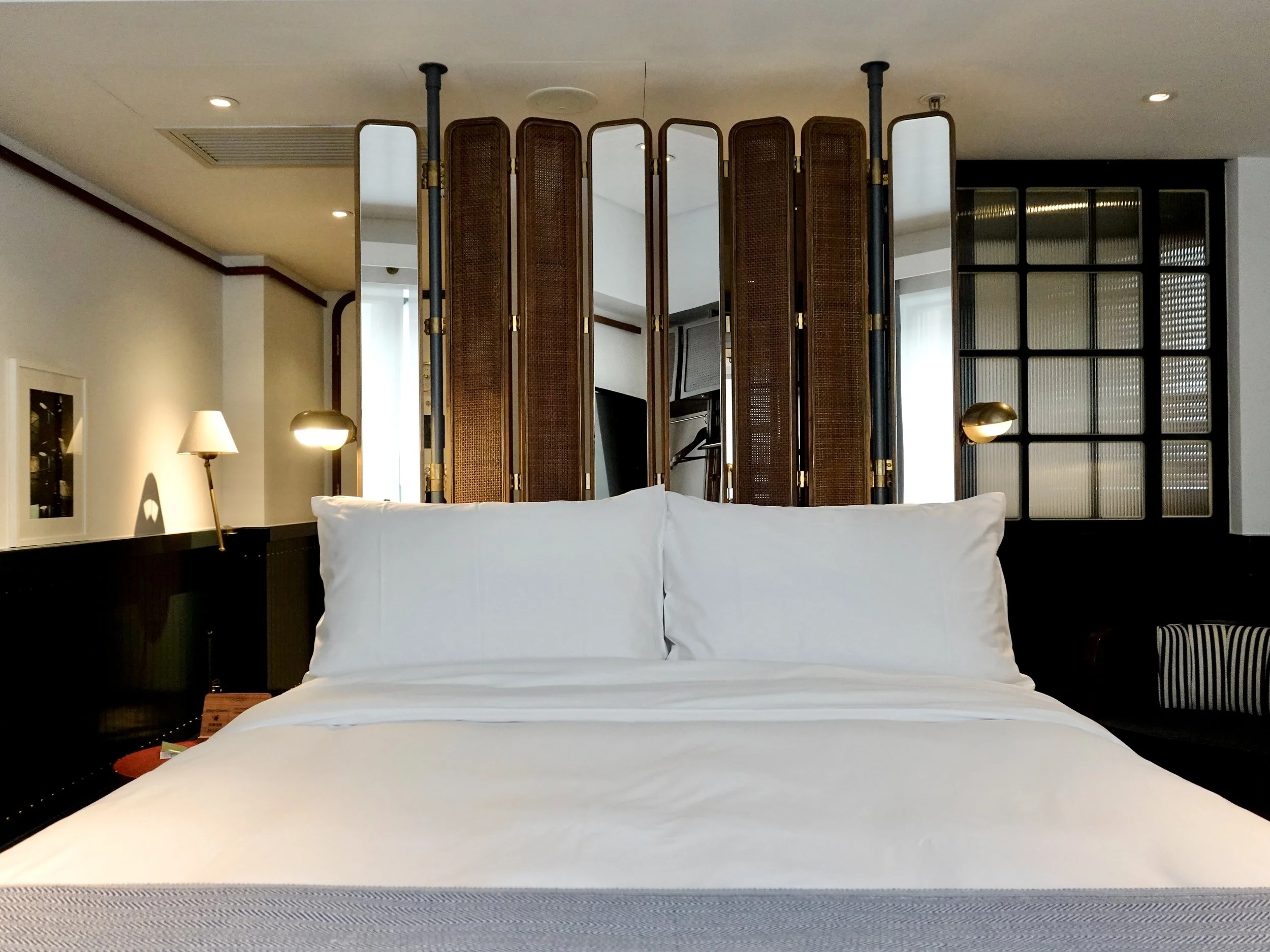 Medium guest room at The Fleming Hong Kong with timber, cane screens, white bed linen and brass lighting
