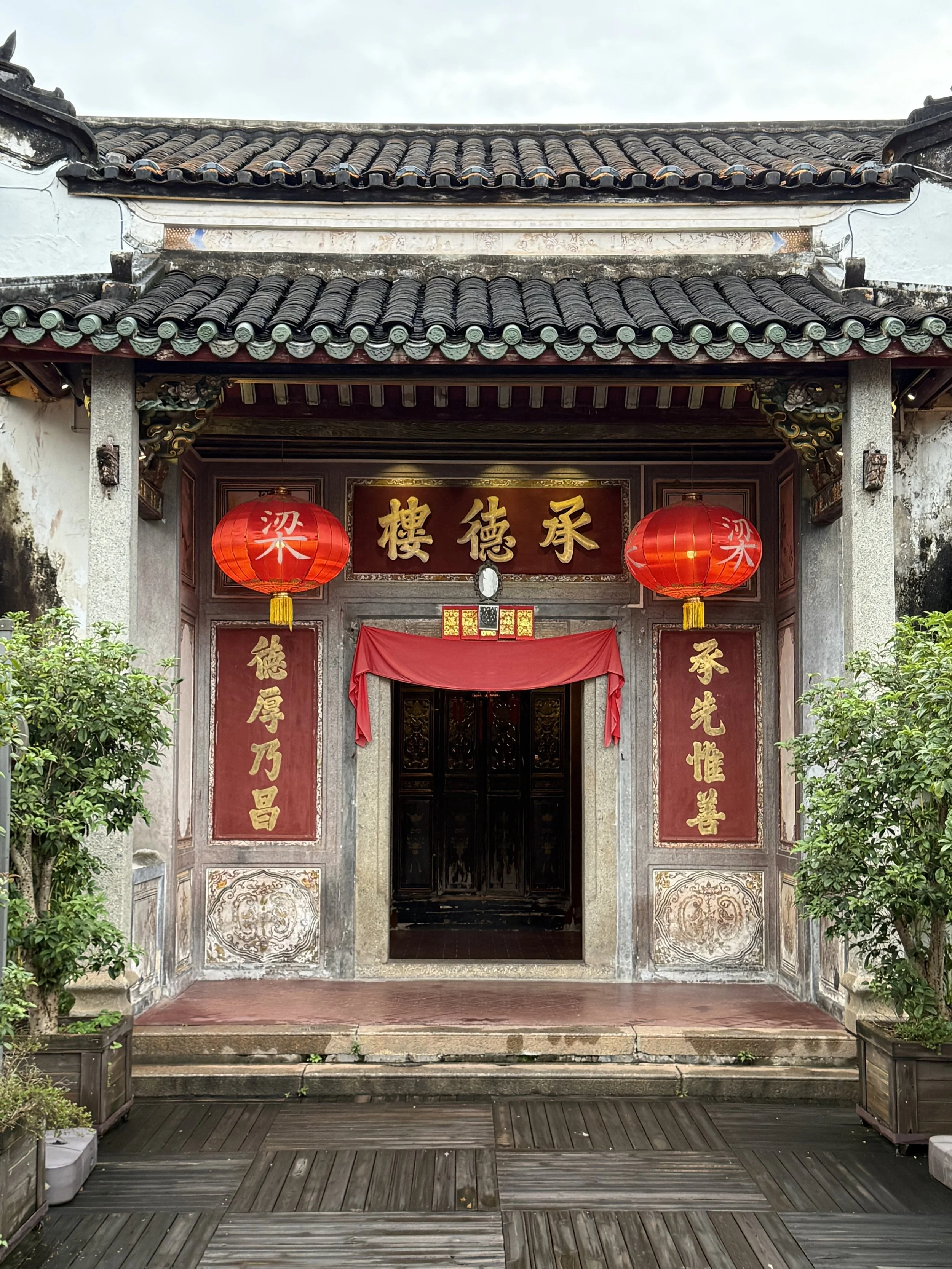Entrance to Chengde Lou at Xingyuan Jiujia in Meizhou, with a Chinese plaque and vertical couplet beside the doorway.