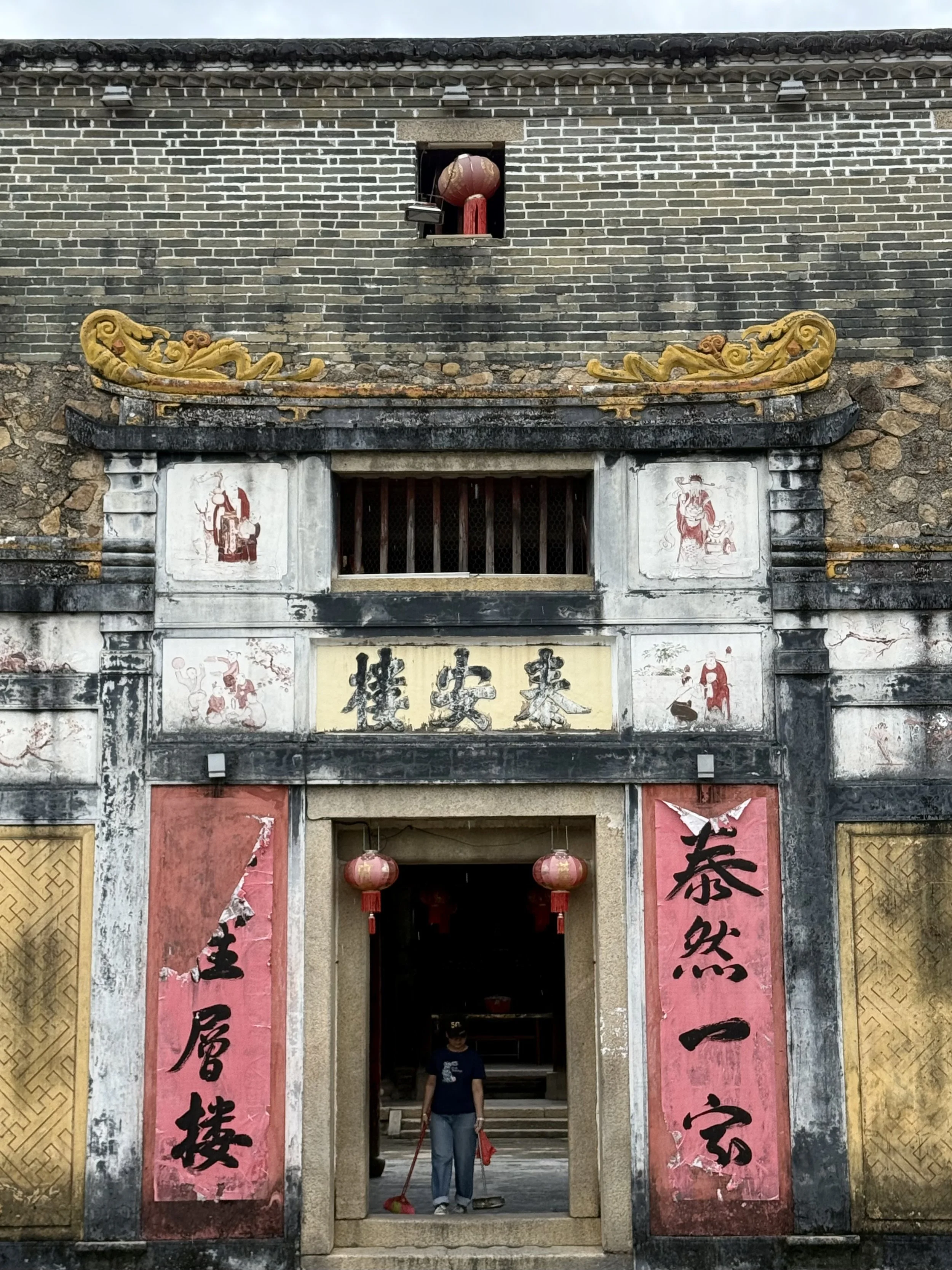 A person carrying out morning cleaning inside the stone courtyards of Tai’an Lou.