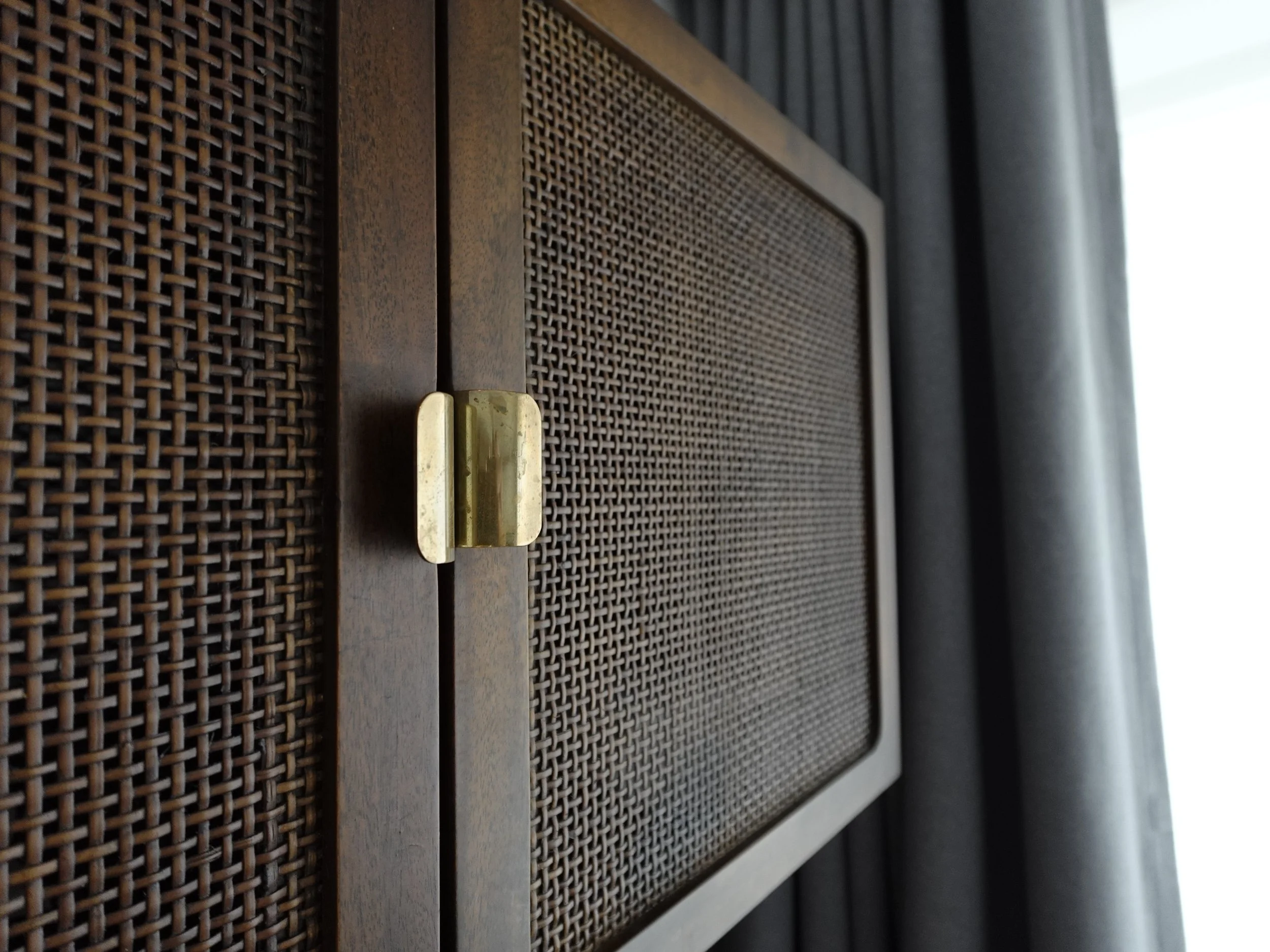 Close\-up of woven cane panel, dark timber and brass hinge inside a room at The Fleming