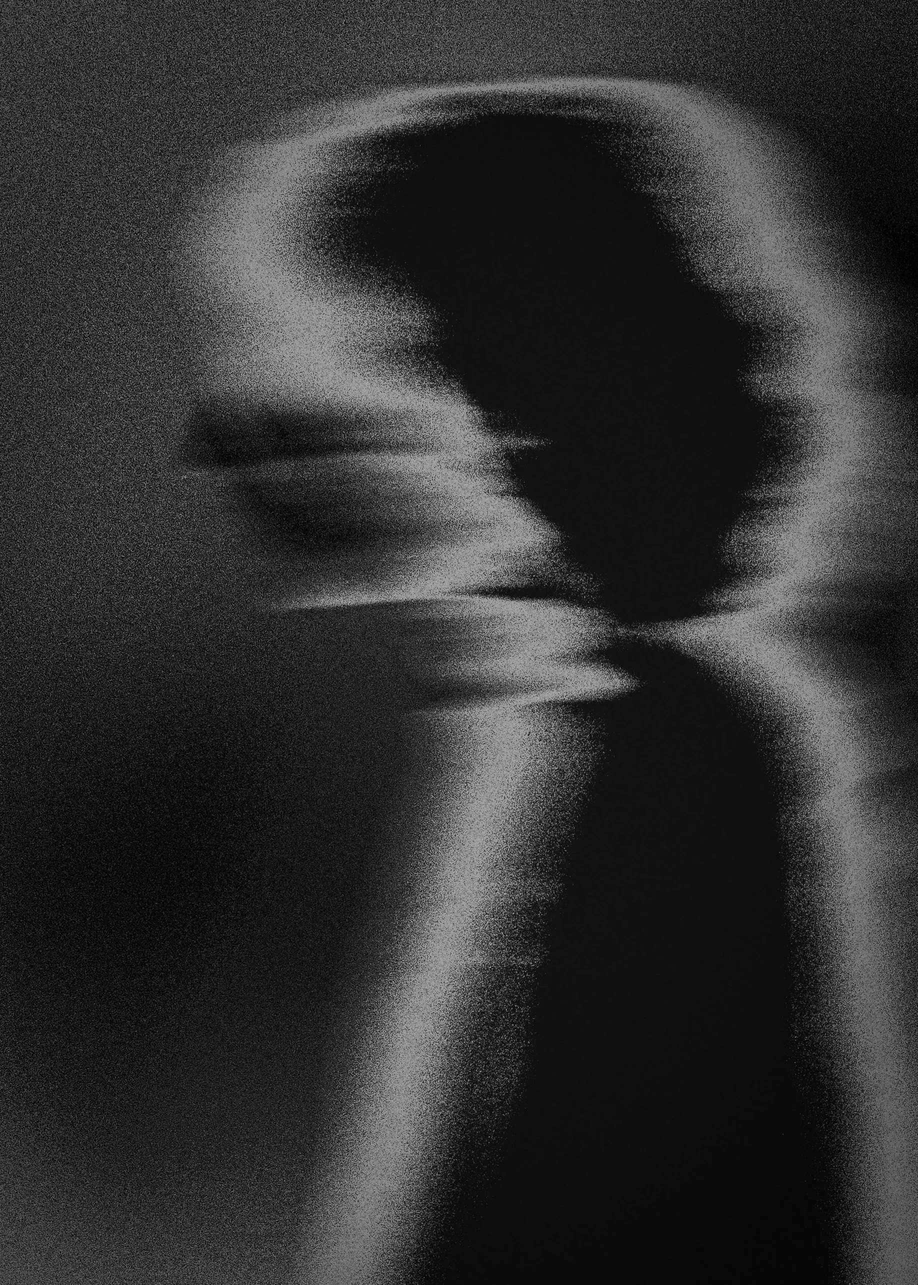 Black and white abstract image with a blurred, circular light pattern.