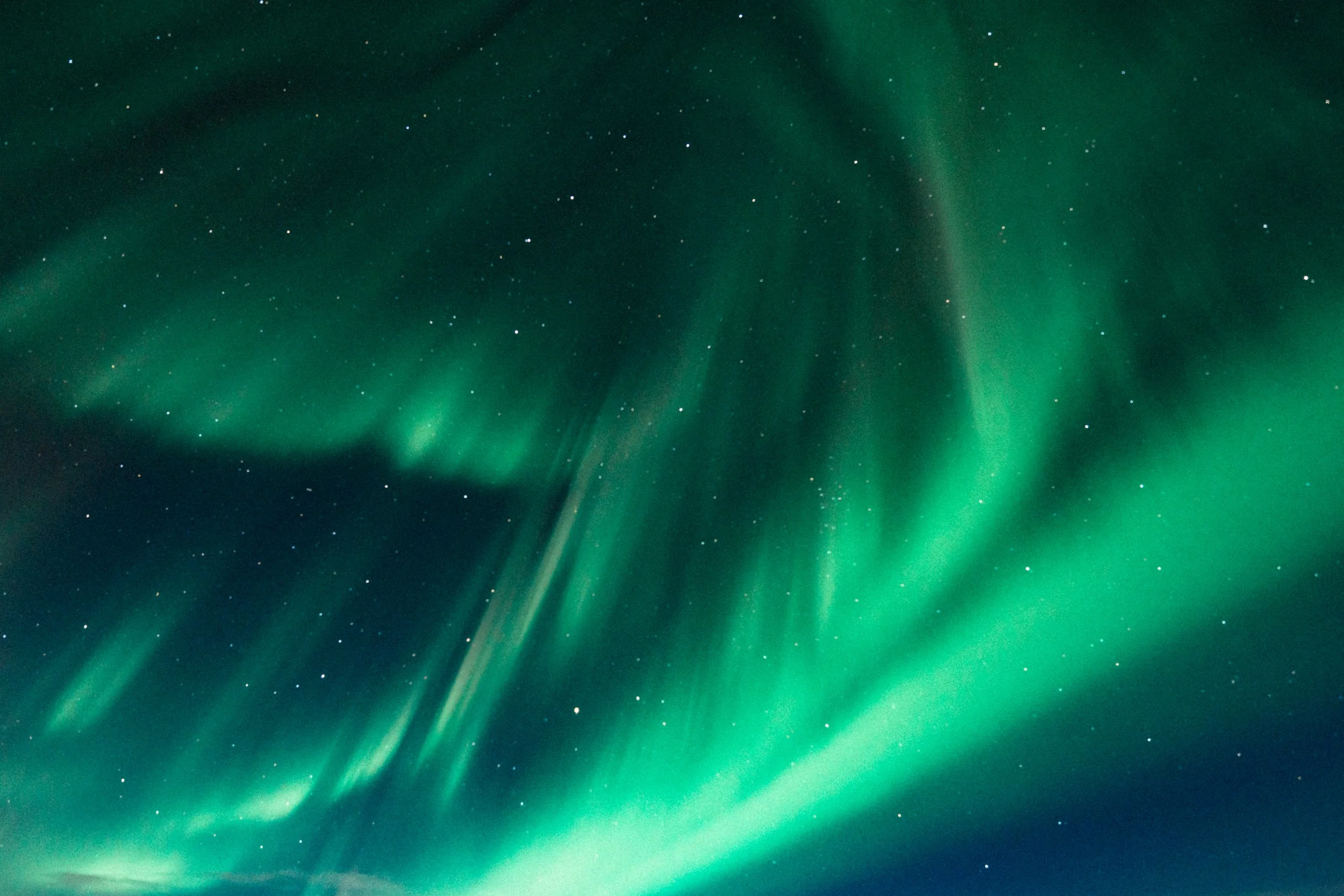 Northern lights (aurora borealis) illuminating the night sky with green hues and starry background.