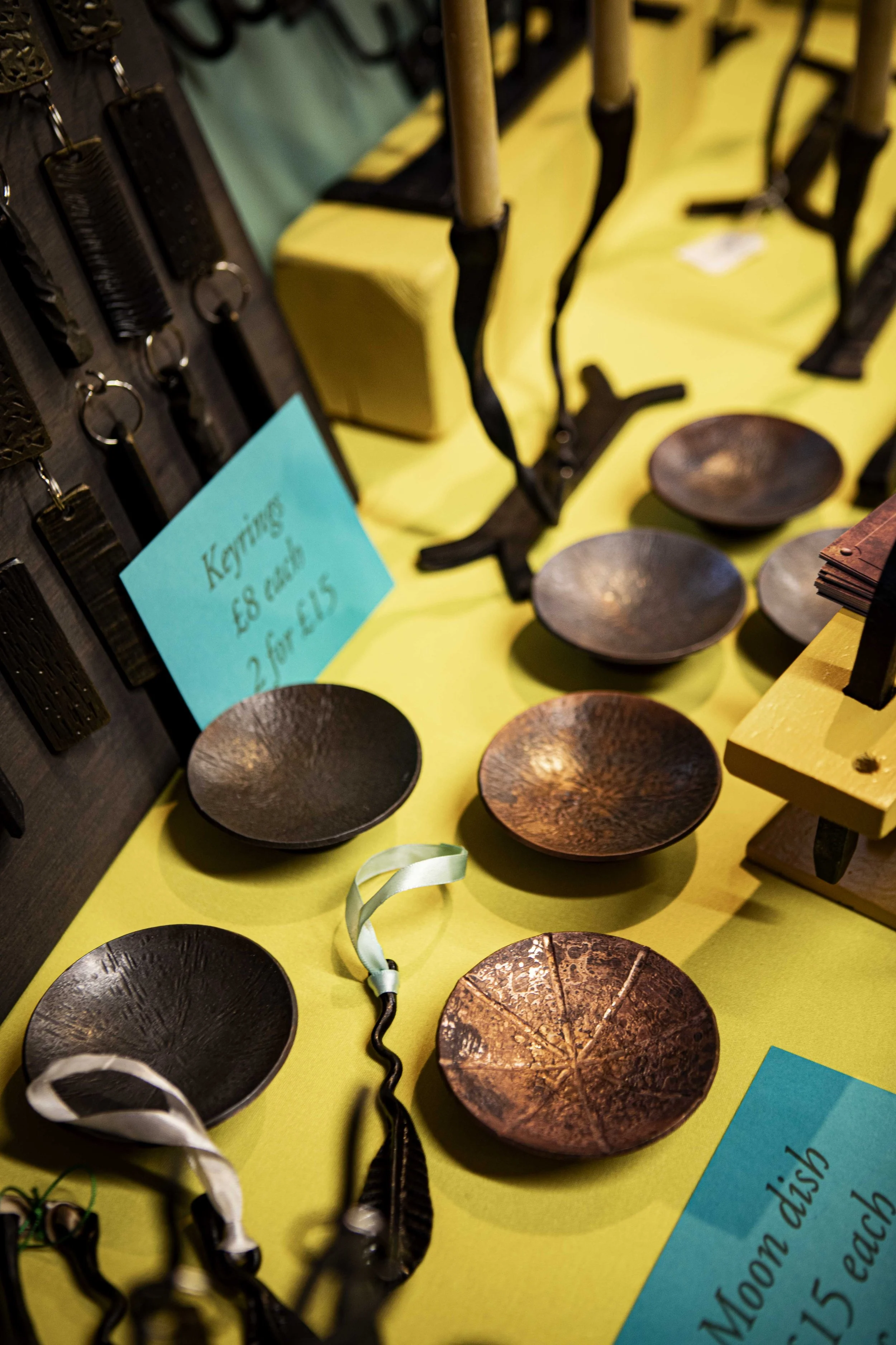 Market stall with rough-coppered steel bowls, key rings, and a candelabra