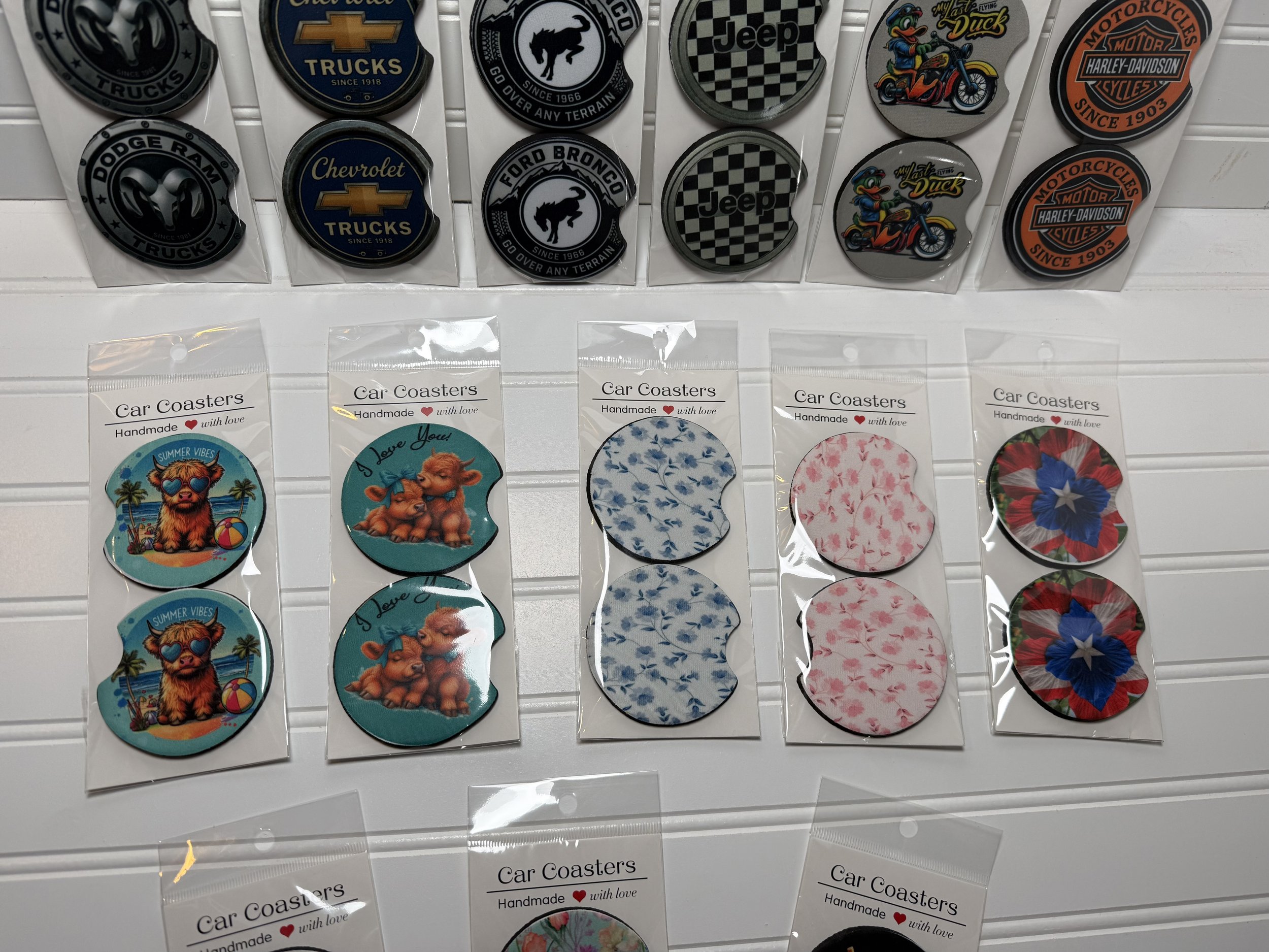 Display of various car coasters featuring cartoon animals, patterns, and logos from car brands.